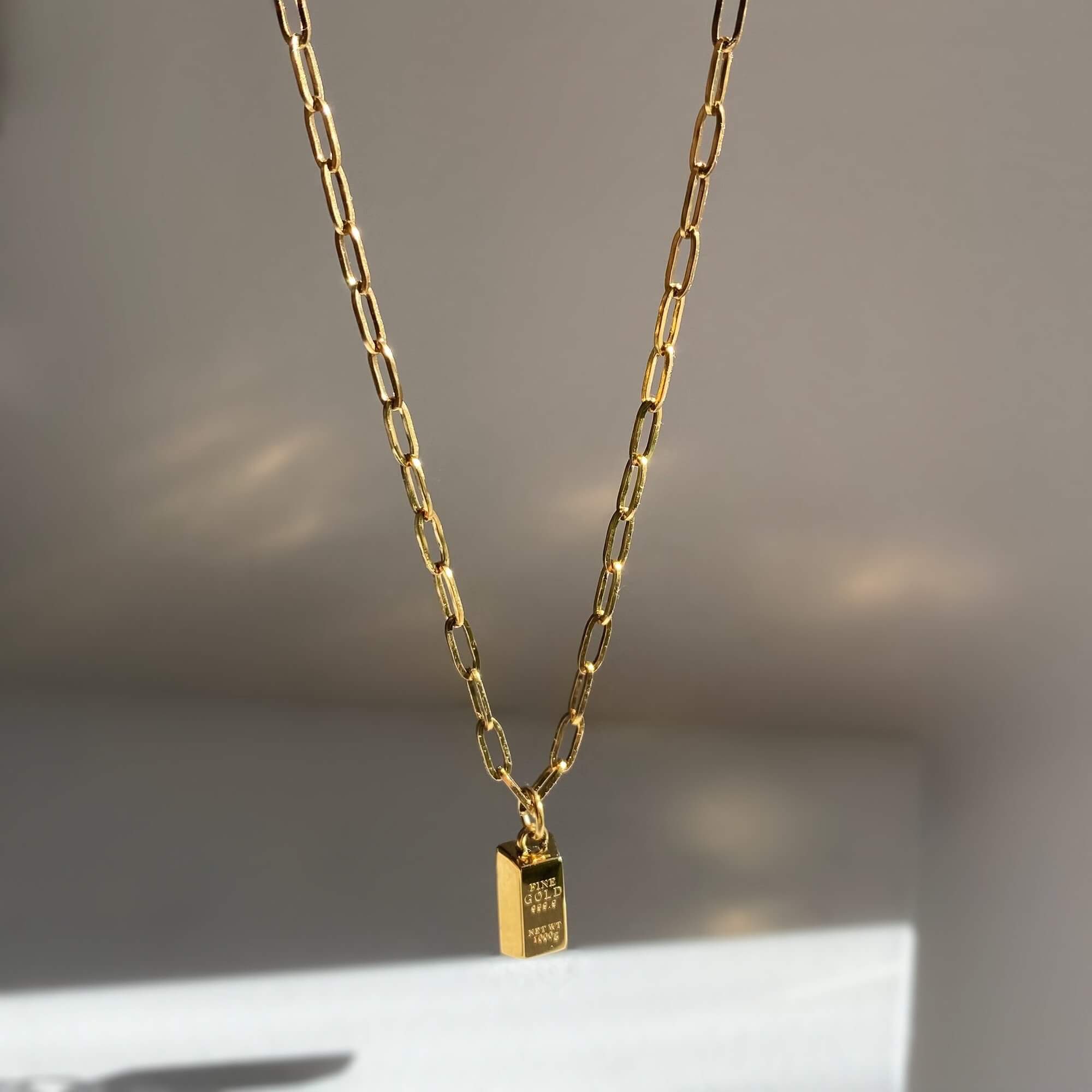 Angled view of the KoldyN 18K gold bar pendant necklace by Kampy Designs, highlighting its reflective finish and contemporary design.