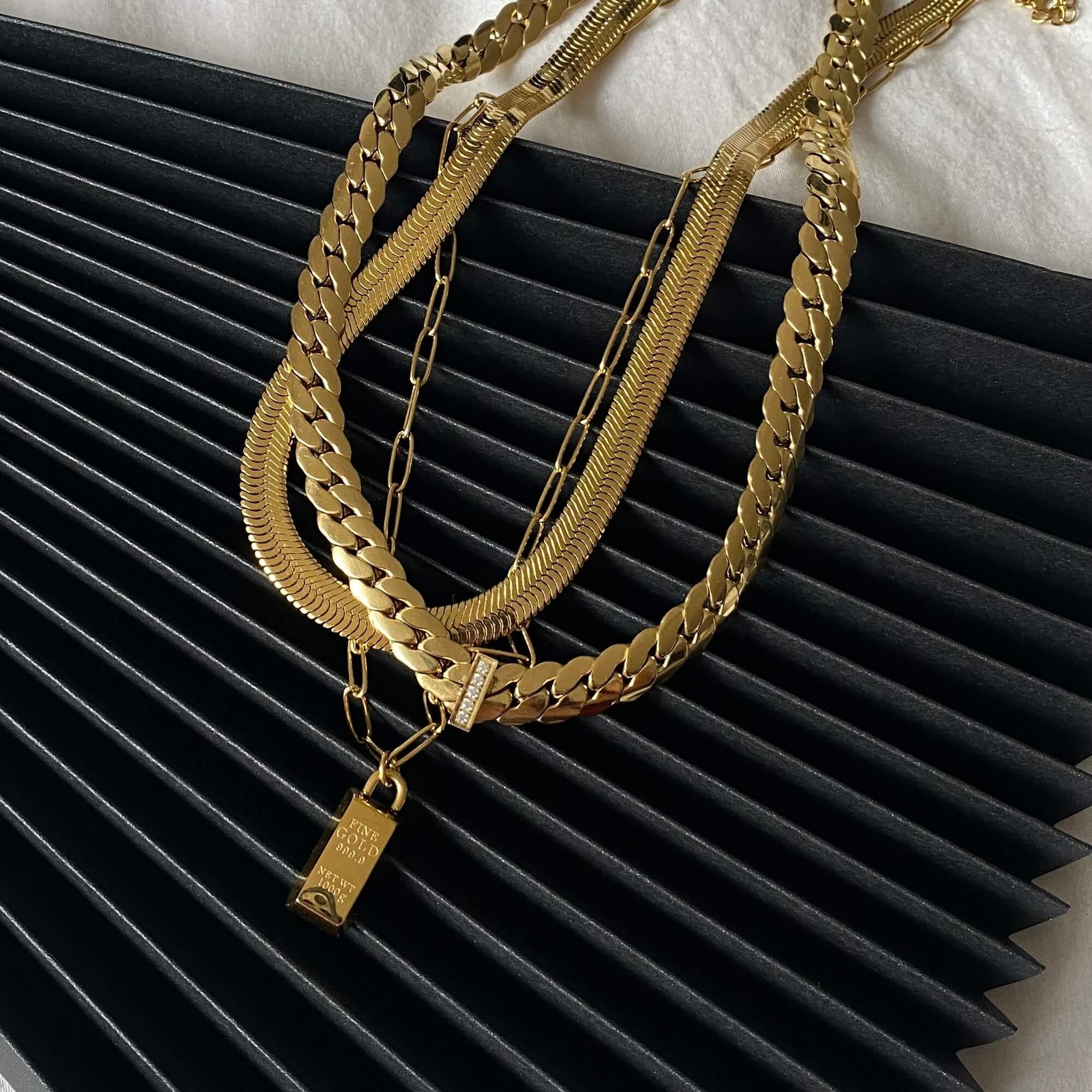 The KoldyN 18K gold bar pendant necklace by Kampy Designs, elegantly stacked with other necklaces for a layered, trendy look.