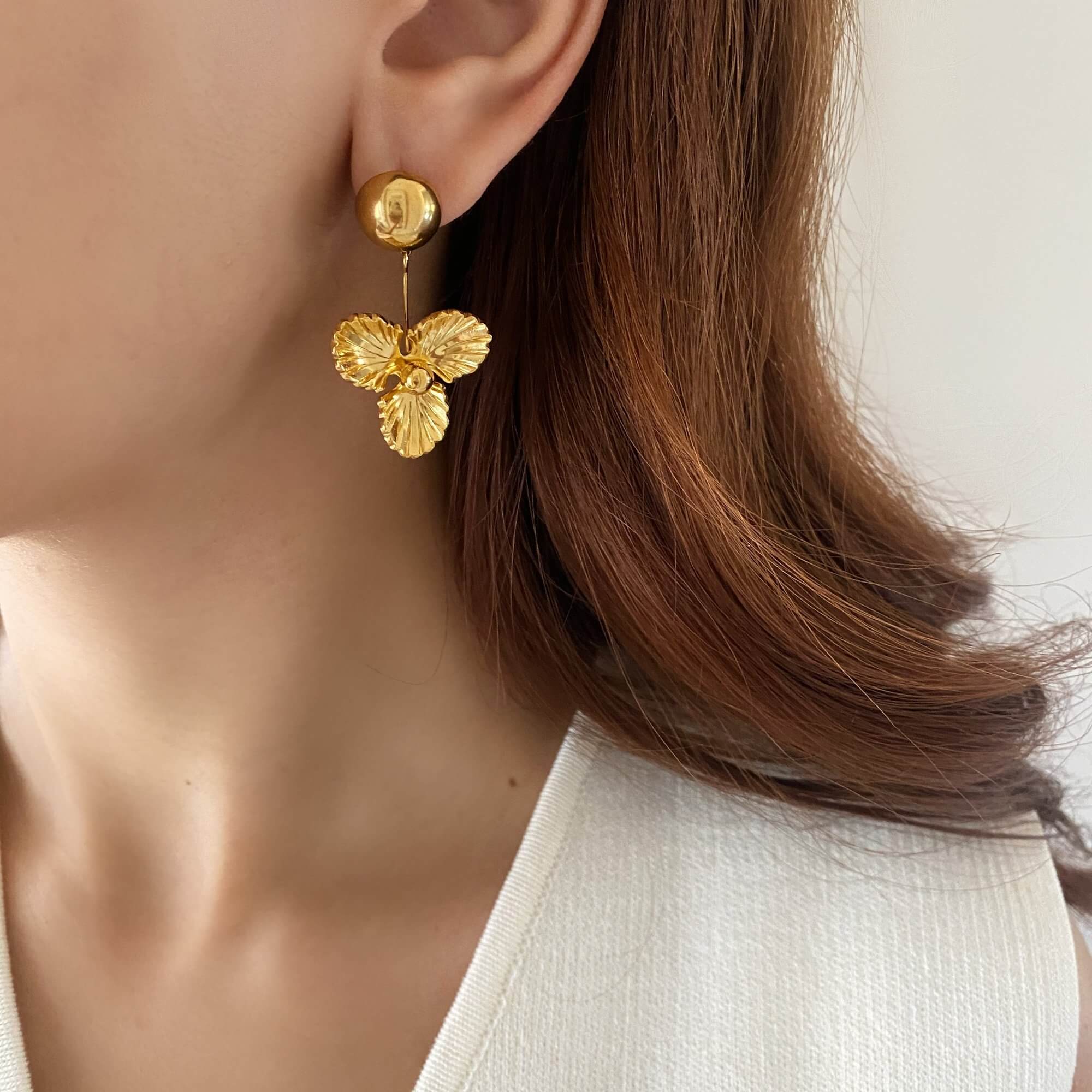 The KloverE 18K gold-plated bold clover drop earrings by Kampy Designs, elegantly worn to showcase their timeless and eye-catching appeal.