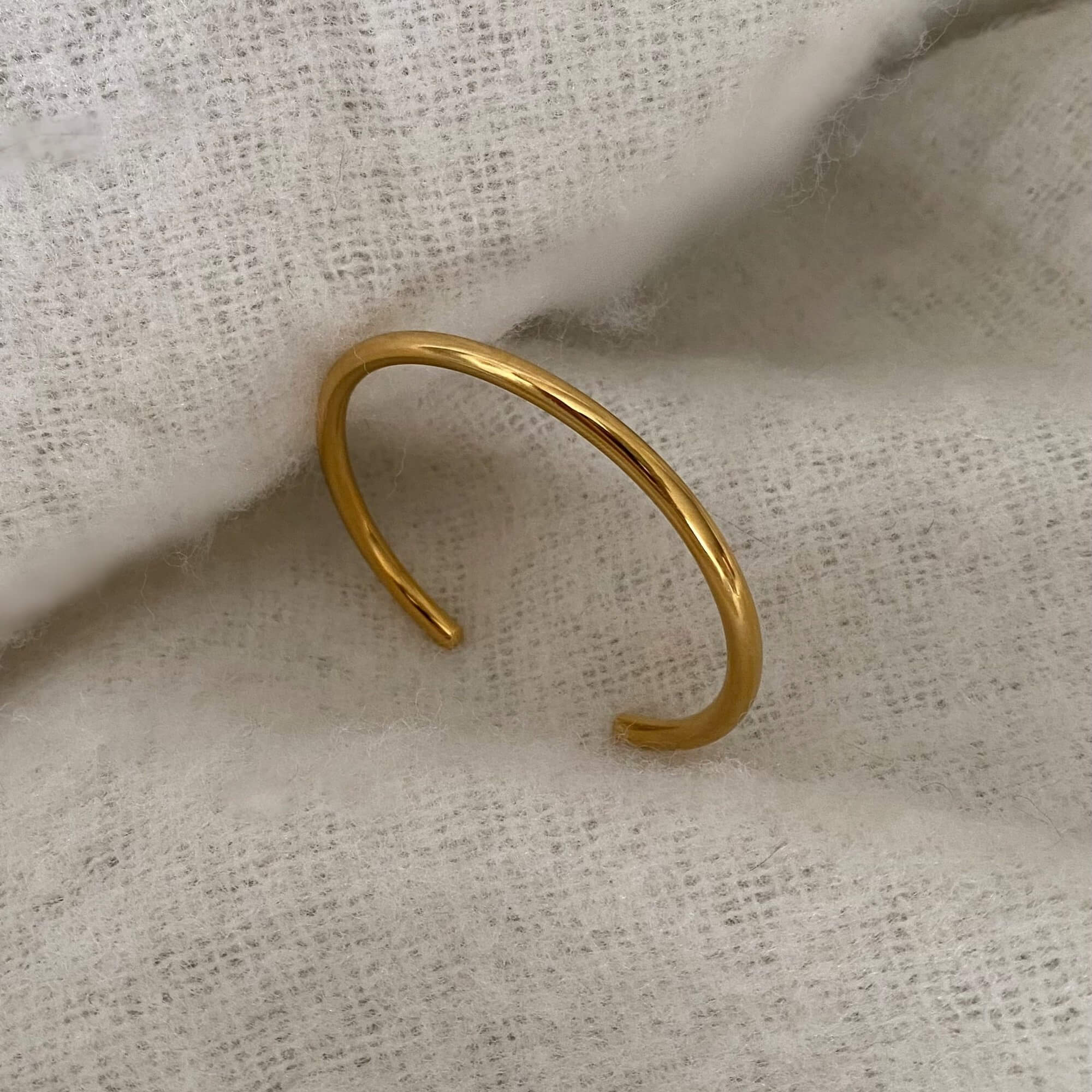 Side view of the KutesyB 18K gold-plated cuff bangle bracelet by Kampy Designs, highlighting its slim, open-ended design.