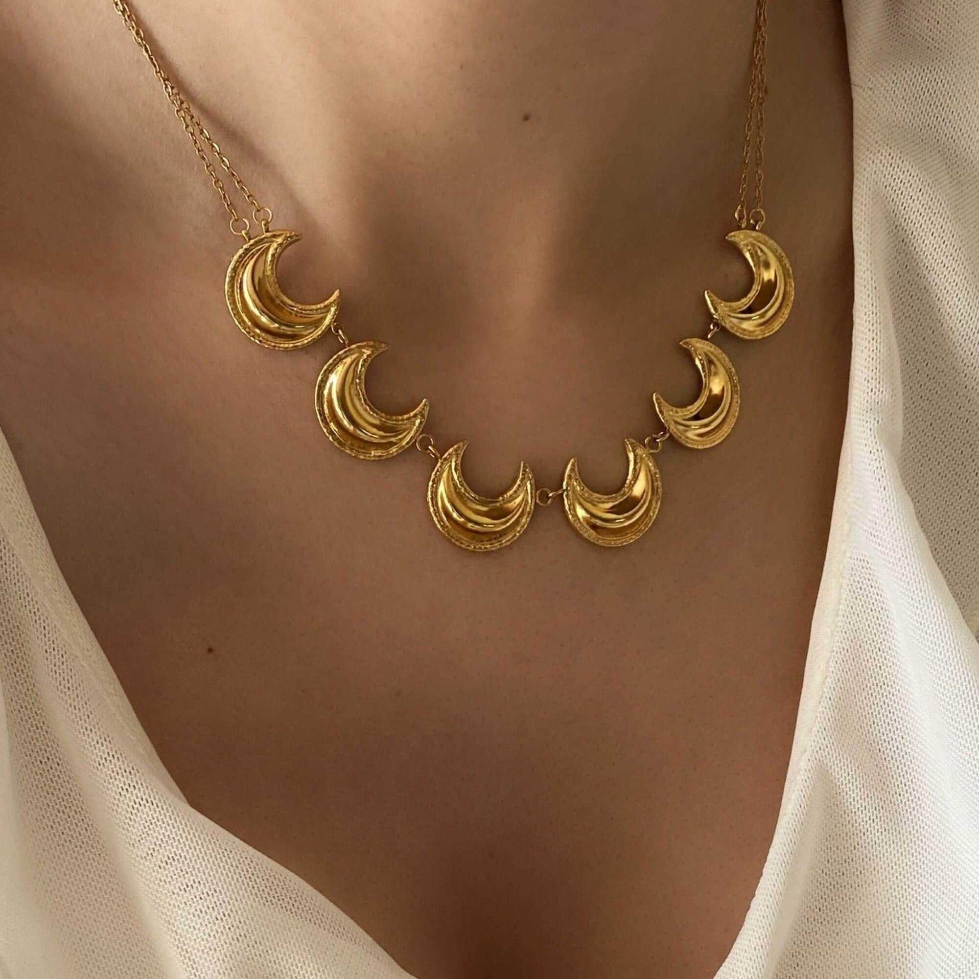 The KrescentN 18K gold-plated moon charm choker necklace by Kampy Designs, elegantly worn to showcase its celestial moon charm and luxurious gold chain.