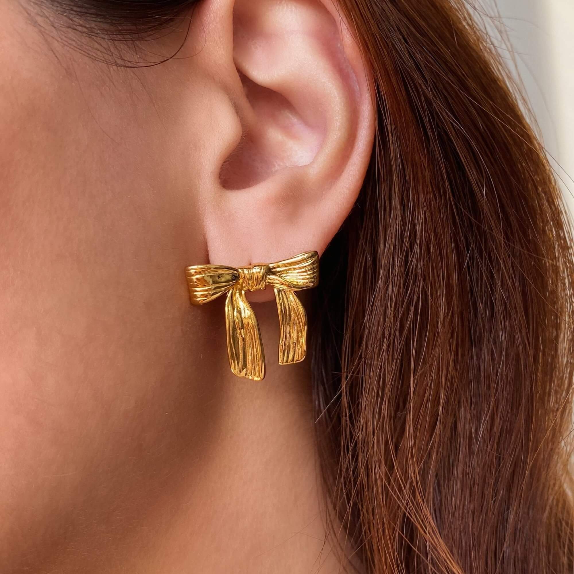 Side view of the KawlaE 18K gold-plated ribbon stud earrings by Kampy Designs, highlighting their delicate bow shape and polished gold finish.