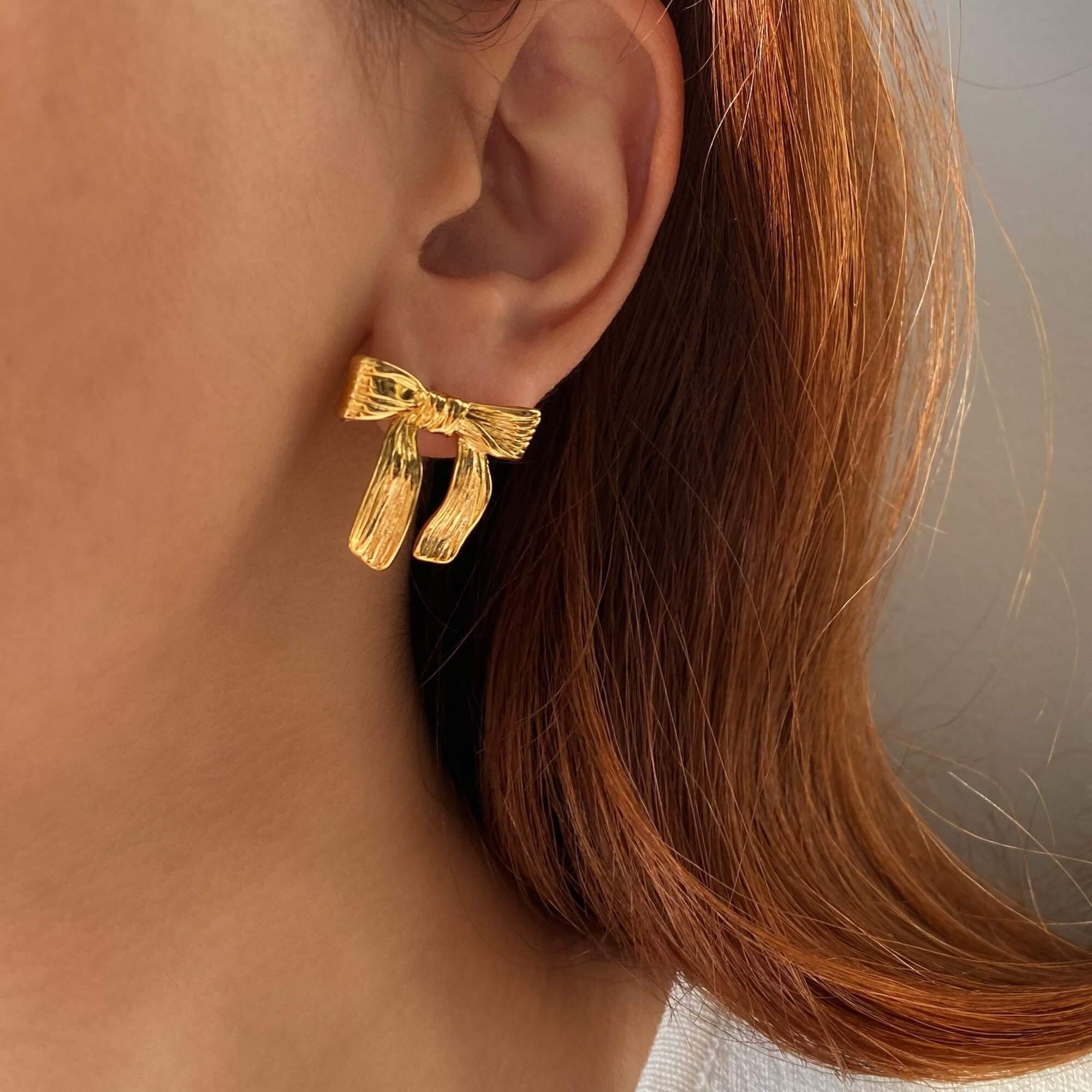 The KawlaE 18K gold-plated ribbon stud earrings by Kampy Designs, beautifully worn to highlight their delicate yet statement-making appeal.