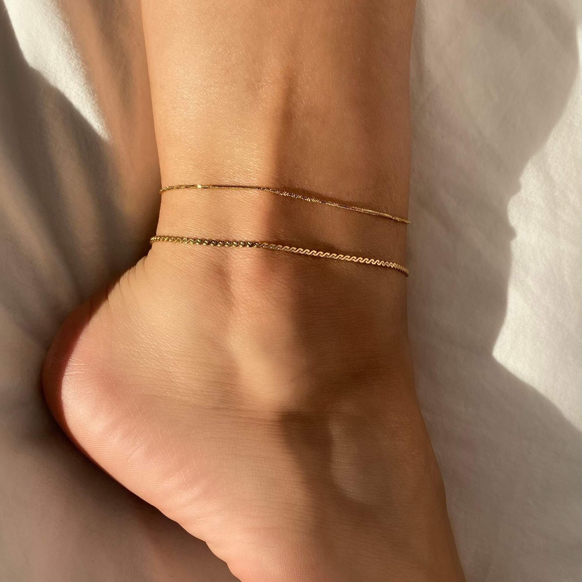 Stacked view of the KasaA 18K gold-plated thin chain anklet by Kampy Designs, styled with multiple anklets for a chic and modern style.