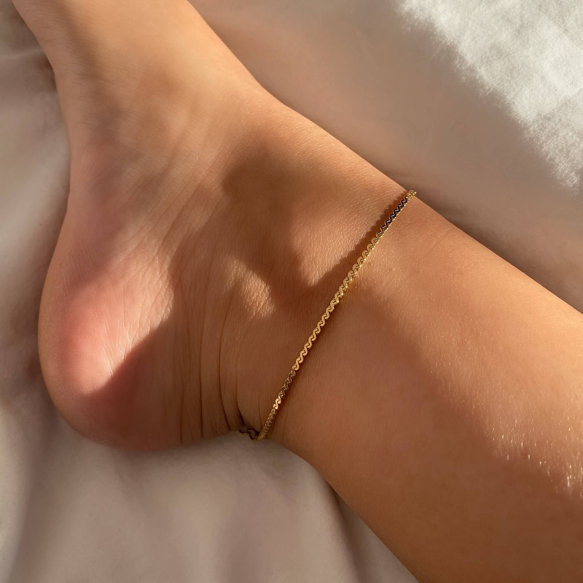 The KasaA 18K gold-plated thin chain anklet by Kampy Designs, elegantly worn to highlight its delicate and timeless beauty.