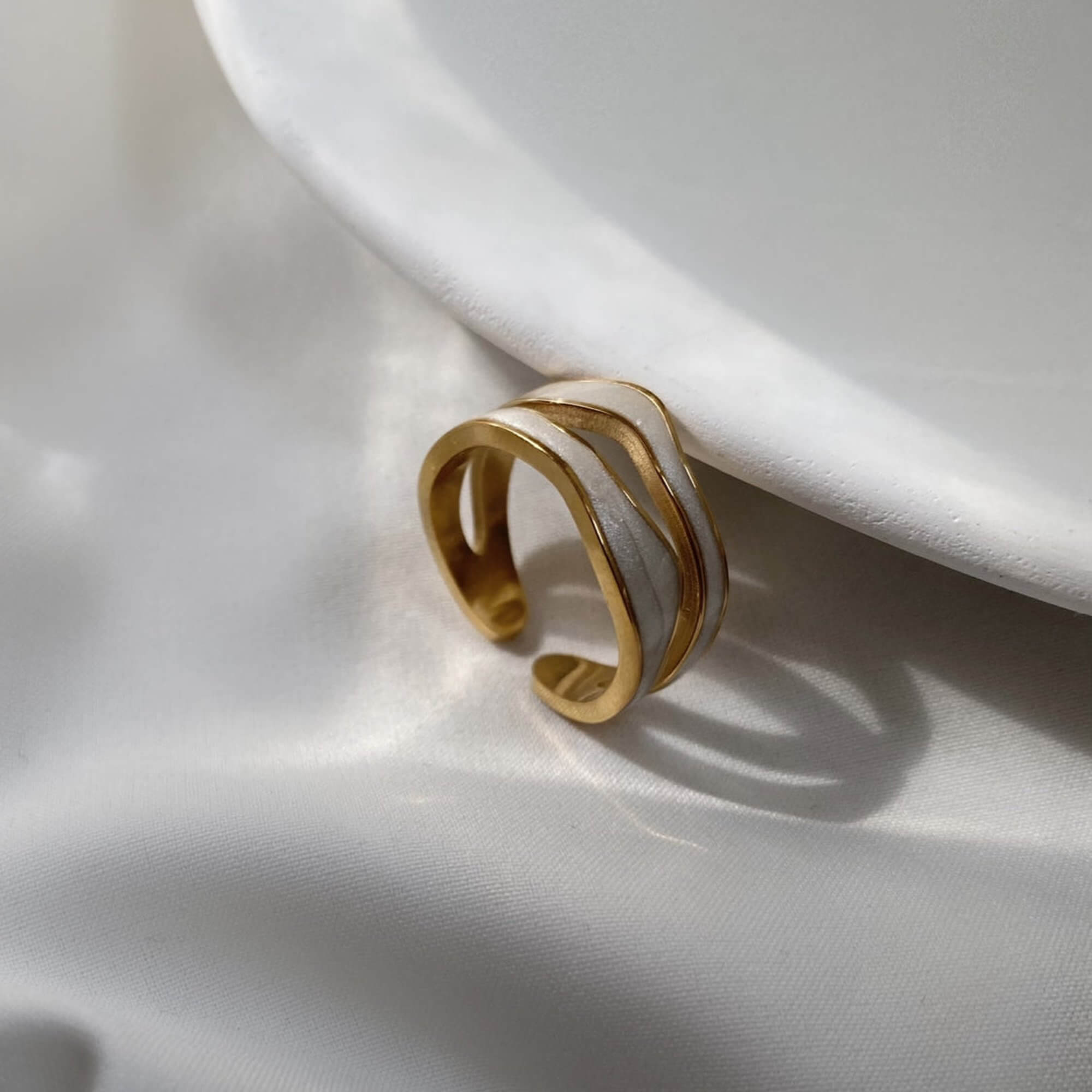 Close-up of the KalaR 18K gold-plated white enamel wave ring by Kampy Designs, capturing its glossy enamel details and elegant gold trim.
