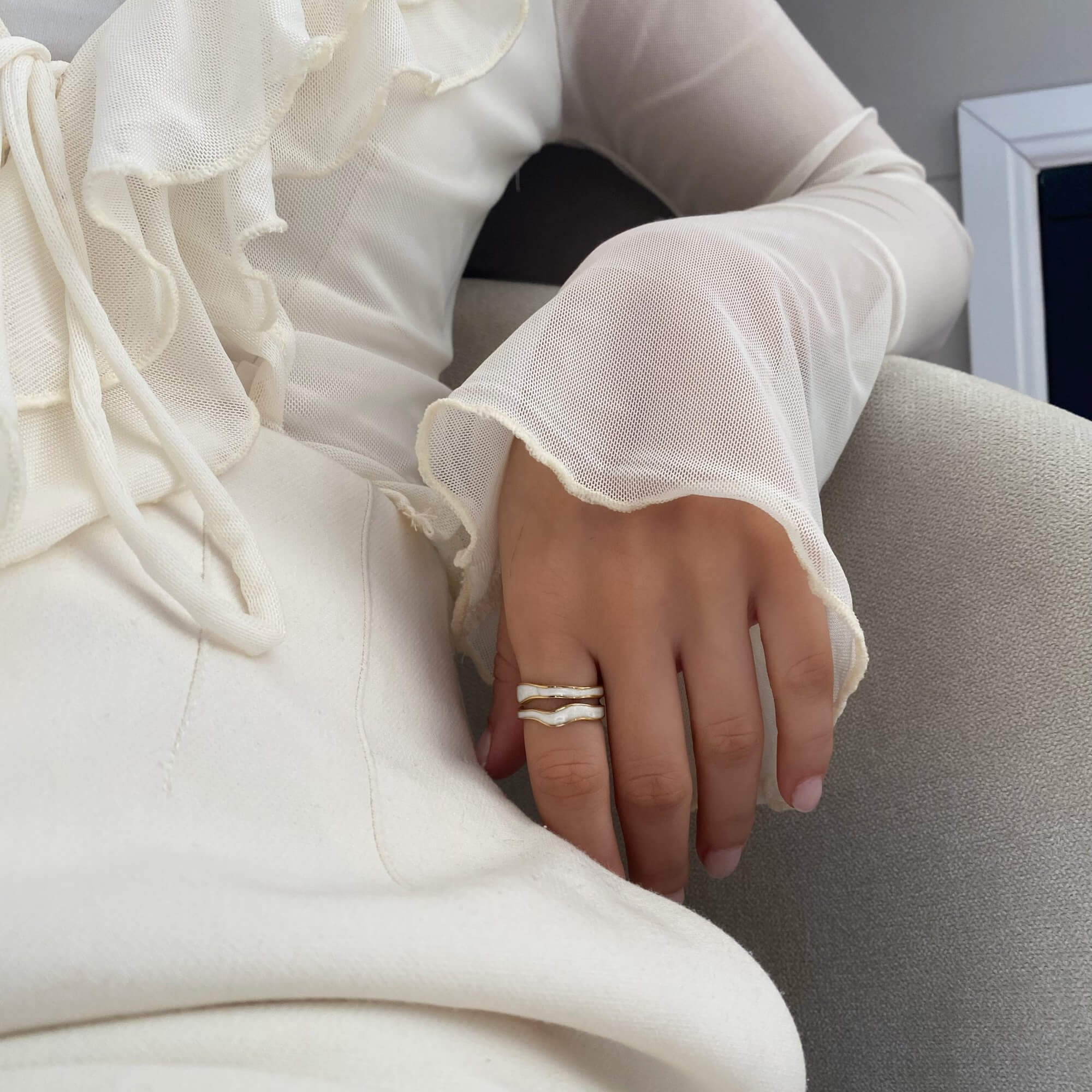 The KalaR 18K gold-plated white enamel wave ring by Kampy Designs, styled with other jewelry for a chic and contemporary look.