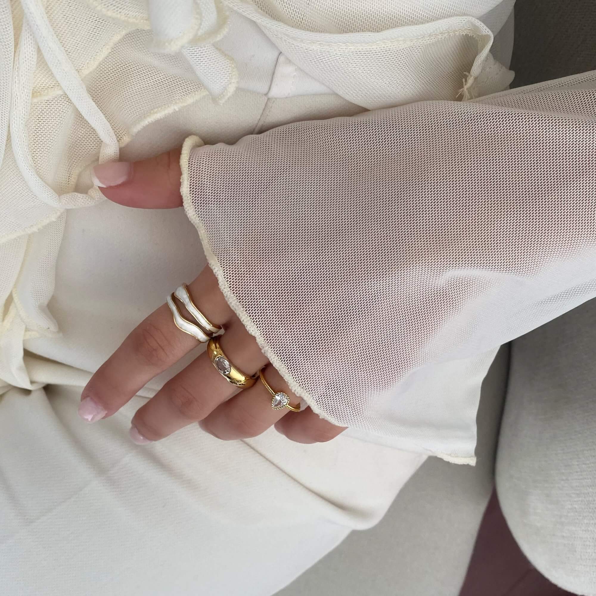 The KalaR 18K gold-plated white enamel wave ring by Kampy Designs, elegantly worn to highlight its stylish and modern wave shape.