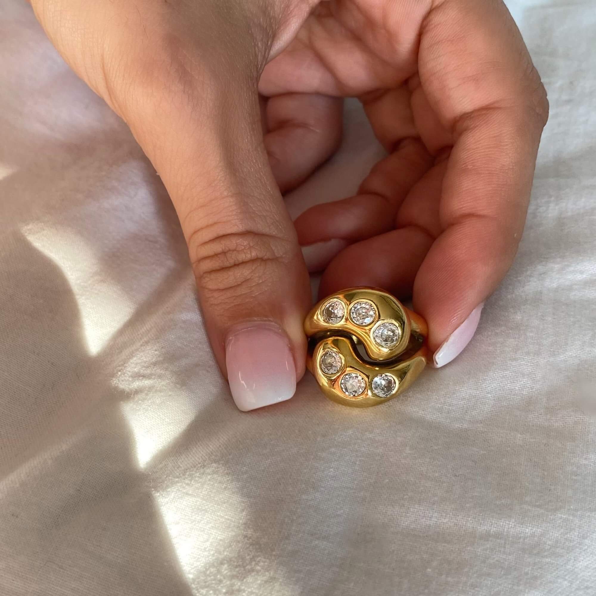 The KassyR 18K gold-plated yin-yang CZ ring by Kampy Designs, delicately held to showcase its fine craftsmanship and eye-catching contrast of black and white stones.