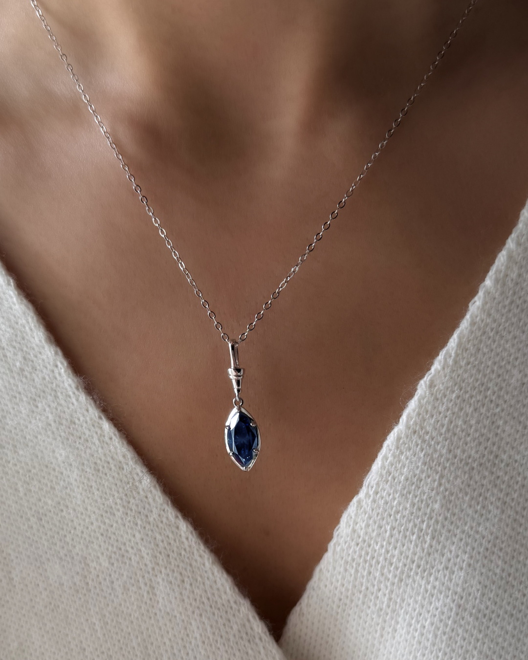 Midnight blue marquise moissanite pendant necklace worn on model with white gold-plated sterling silver chain.