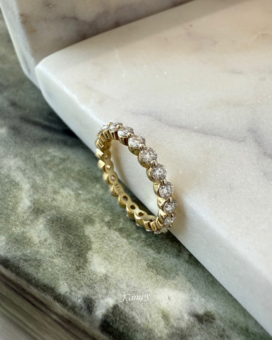 Gold eternity ring with lab grown moissanite on a marble surface