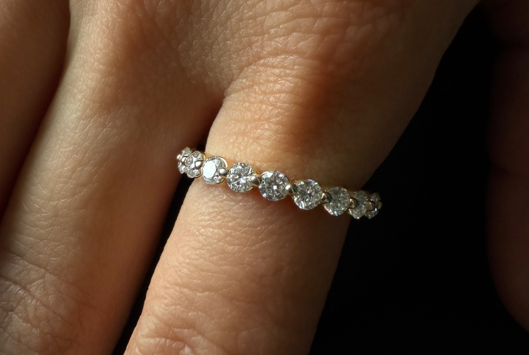 Close up detailed shot of round moissanite eternity band worn on model hand, Kampy Designs