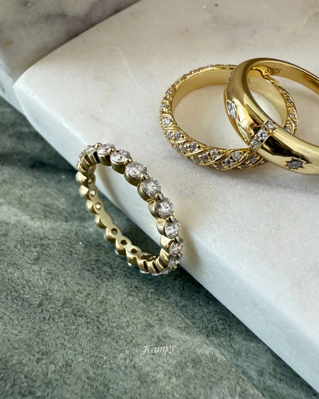Three gold rings with diamond accents on a marble surface