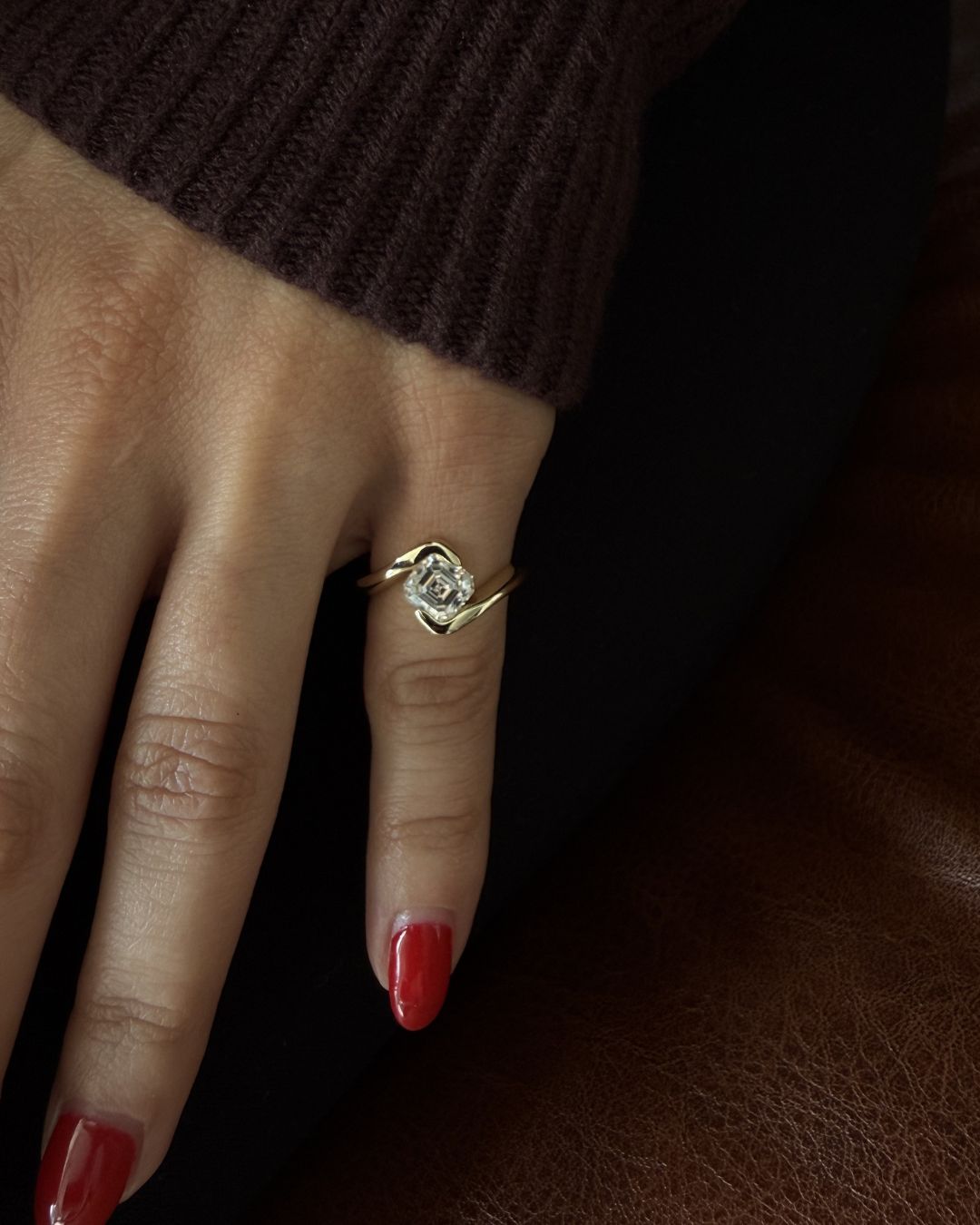 Asscher cut pinky ring worn on hand in a clean minimal luxury styling with soft lighting