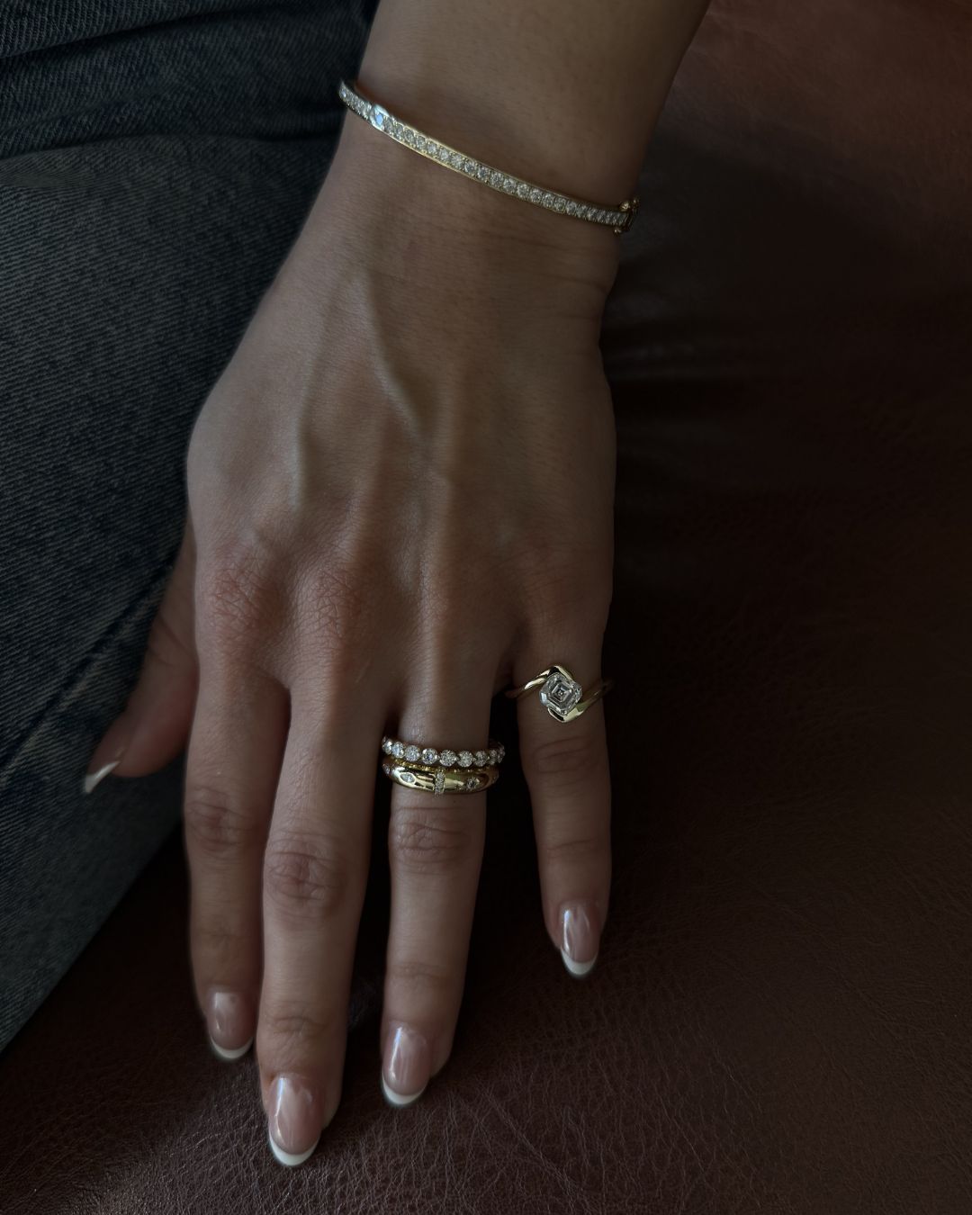 Gold asscher cut ring styled in a stacked look with a tennis band and everyday jewelry pieces