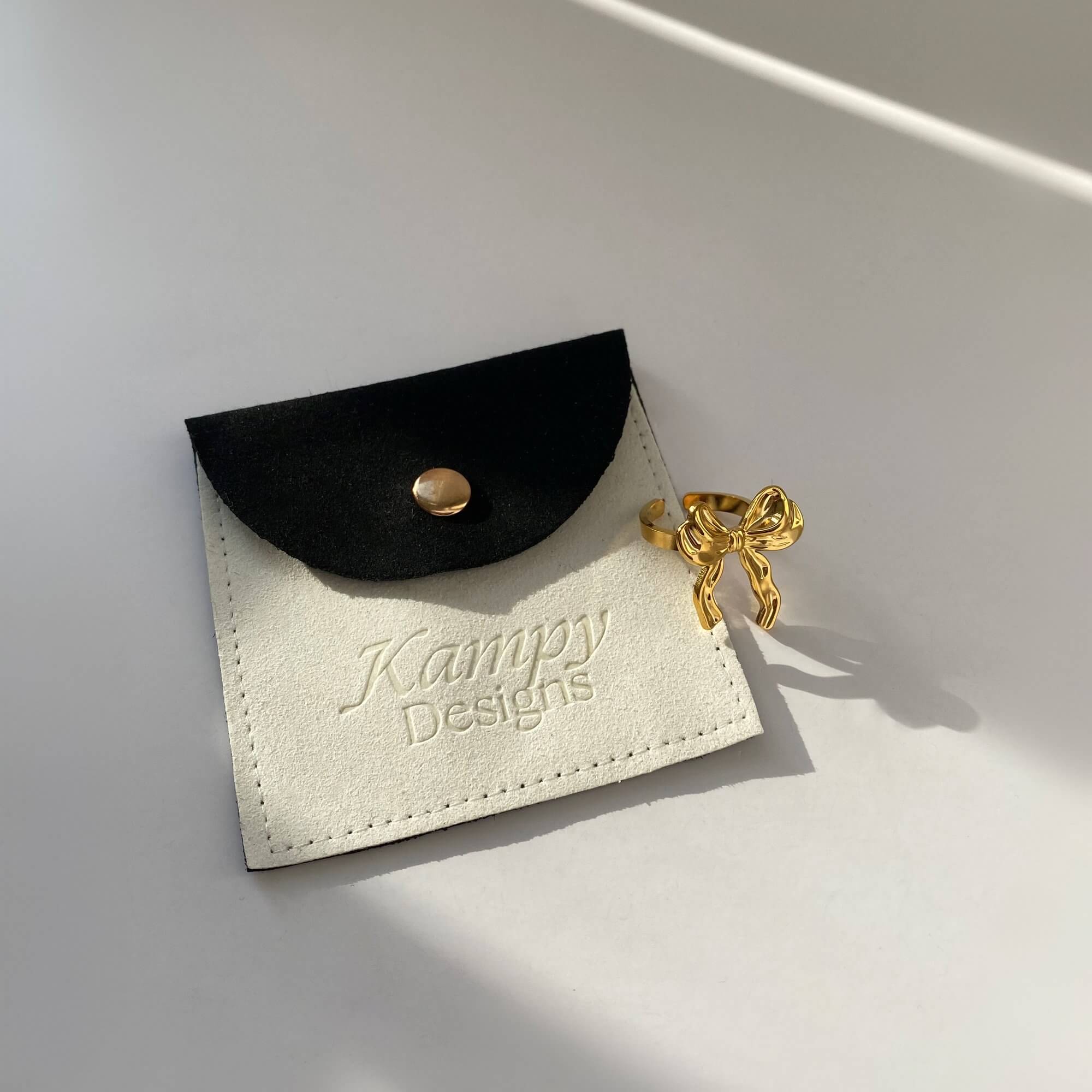 Flat lay of the Kinikir bow statement ring by Kampy Designs, featuring its symmetrical bow form and radiant gold finish.