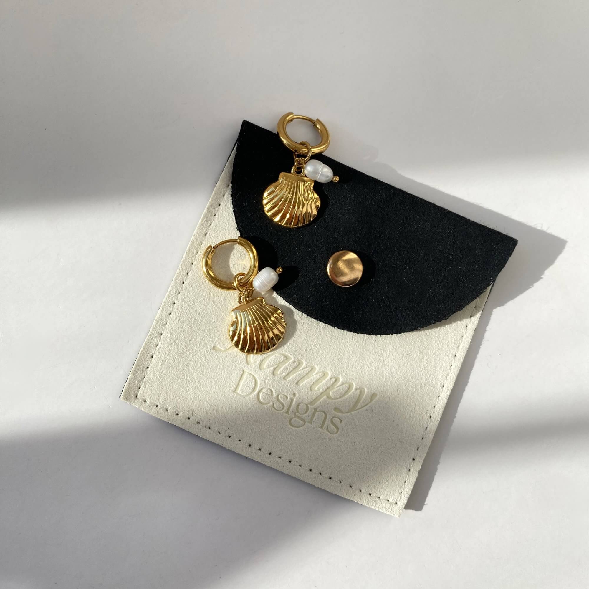 Flat lay of the KlammyE clam hoop earring by Kampy Designs, showing the sculpted shell texture and polished gold-tone finish.