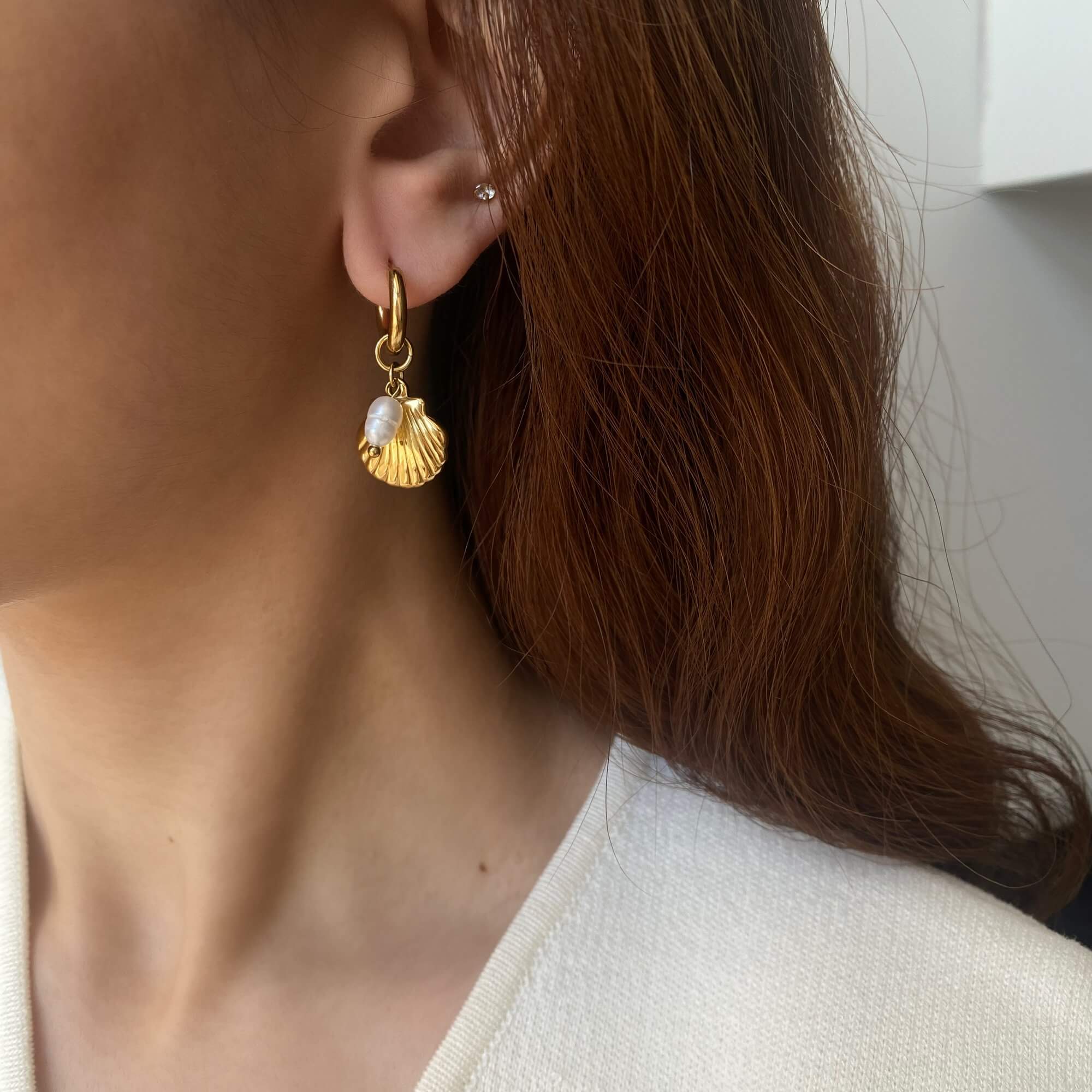 Styled look of KlammyE clam hoop earring by Kampy Designs, worn on model’s ear to highlight its coastal charm and curved shell design.