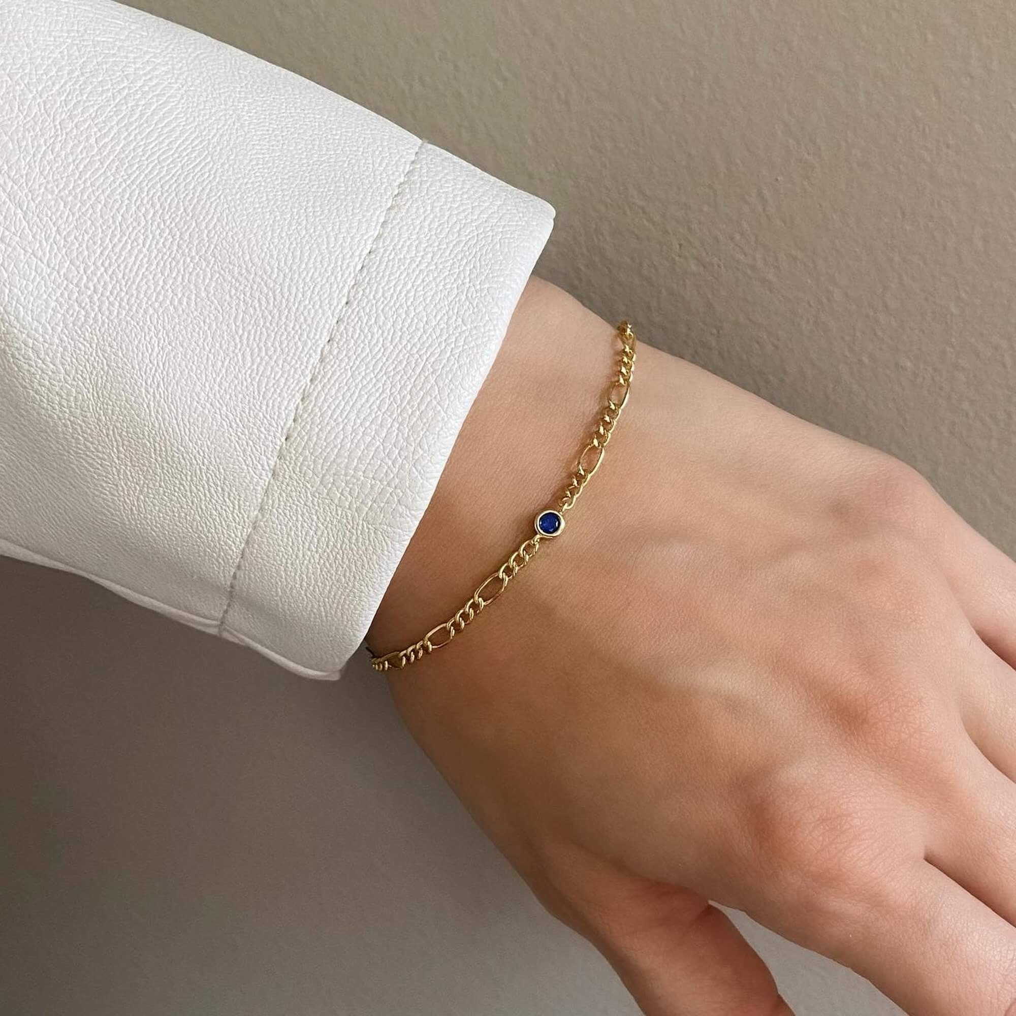 The KianaB CZ gemstone Figaro chain bracelet by Kampy Designs, adorned with a deep sapphire-blue cubic zirconia stone for a luxurious touch.