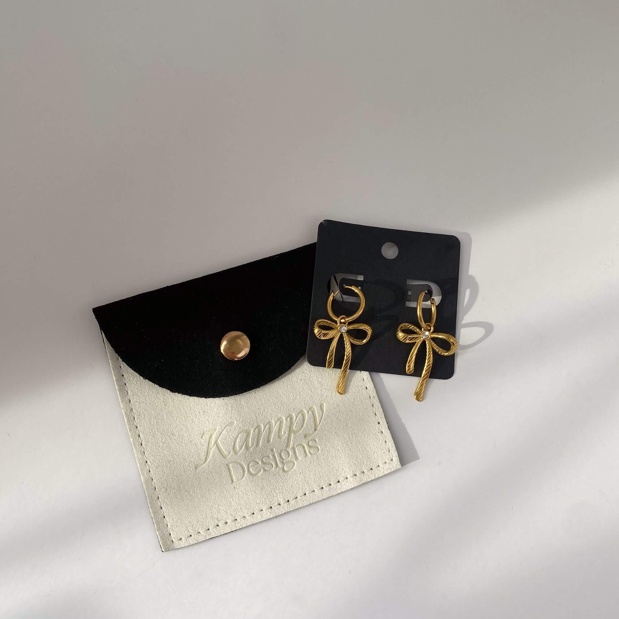 KrissaE dainty bow dangle earrings by Kampy Designs, displayed on branded packaging for a polished and giftable presentation.