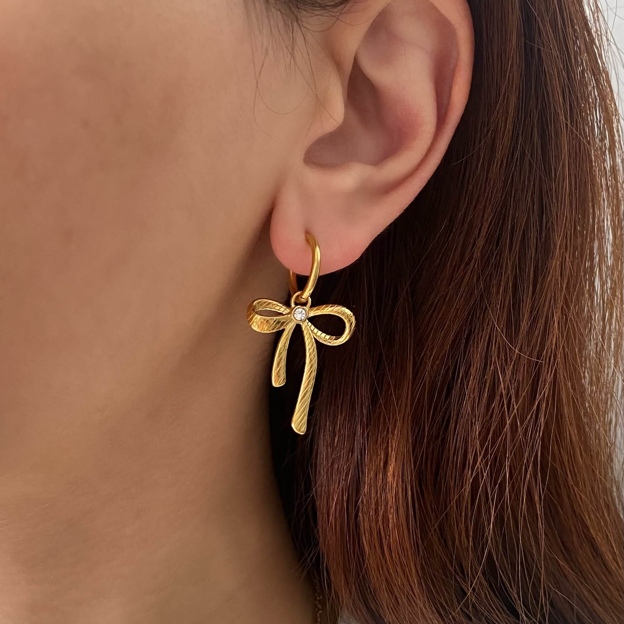 Close-up of KrissaE dainty bow dangle earrings by Kampy Designs, styled on model’s ear to highlight the refined feminine touch.
