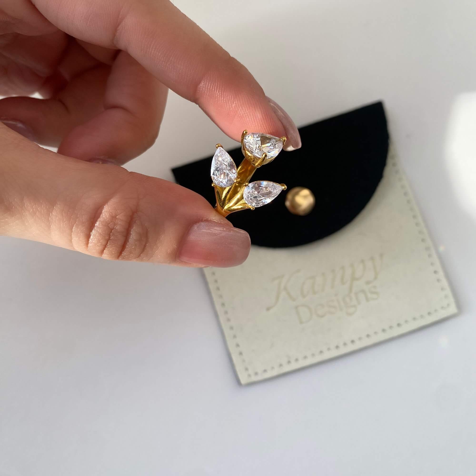 Angled view of the KipsyR floral vine ring by Kampy Designs, held by the model to showcase its raised floral design and vine curves.