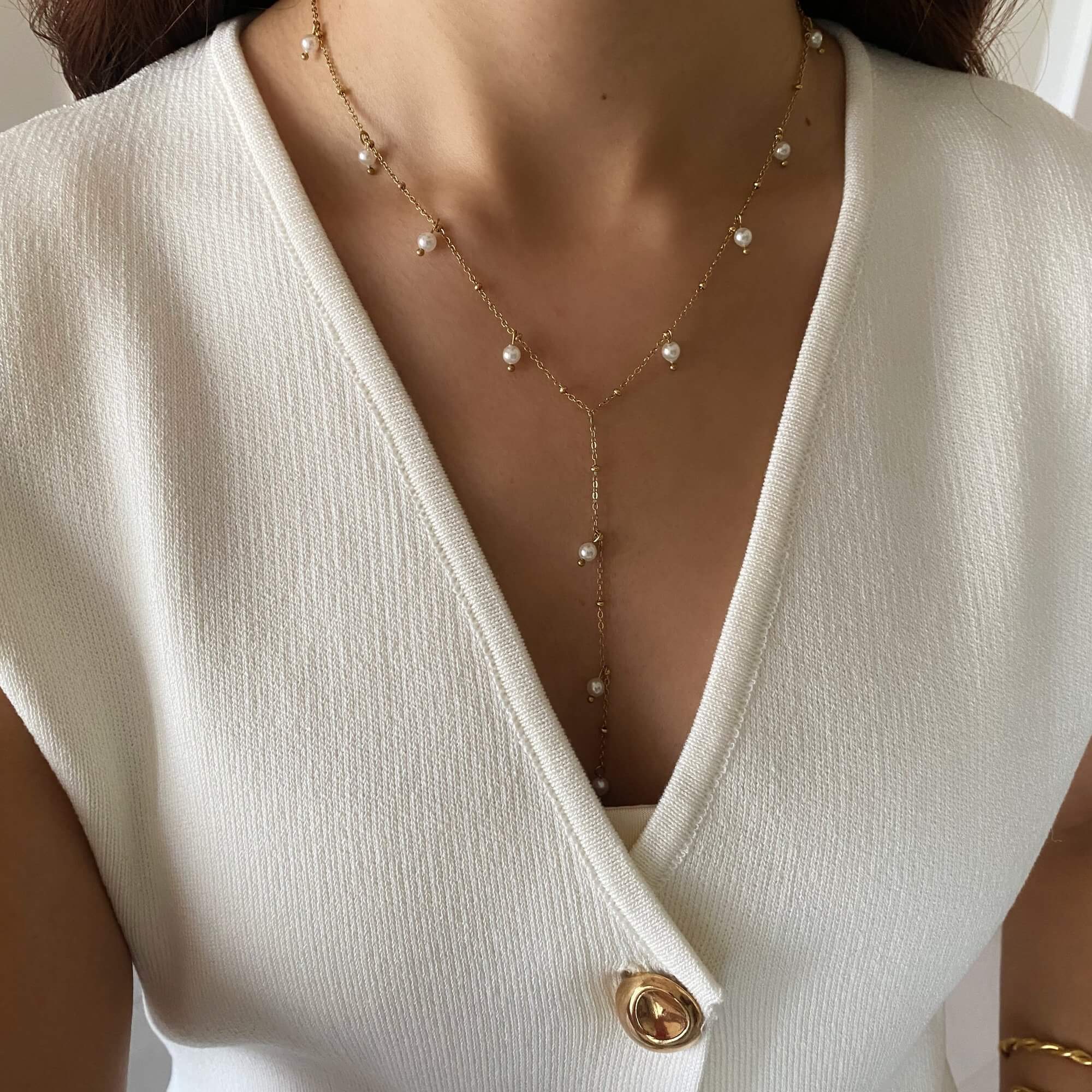 The KleopatraN freshwater pearl charm lariat necklace by Kampy Designs, gracefully worn to highlight its refined and sophisticated drape.