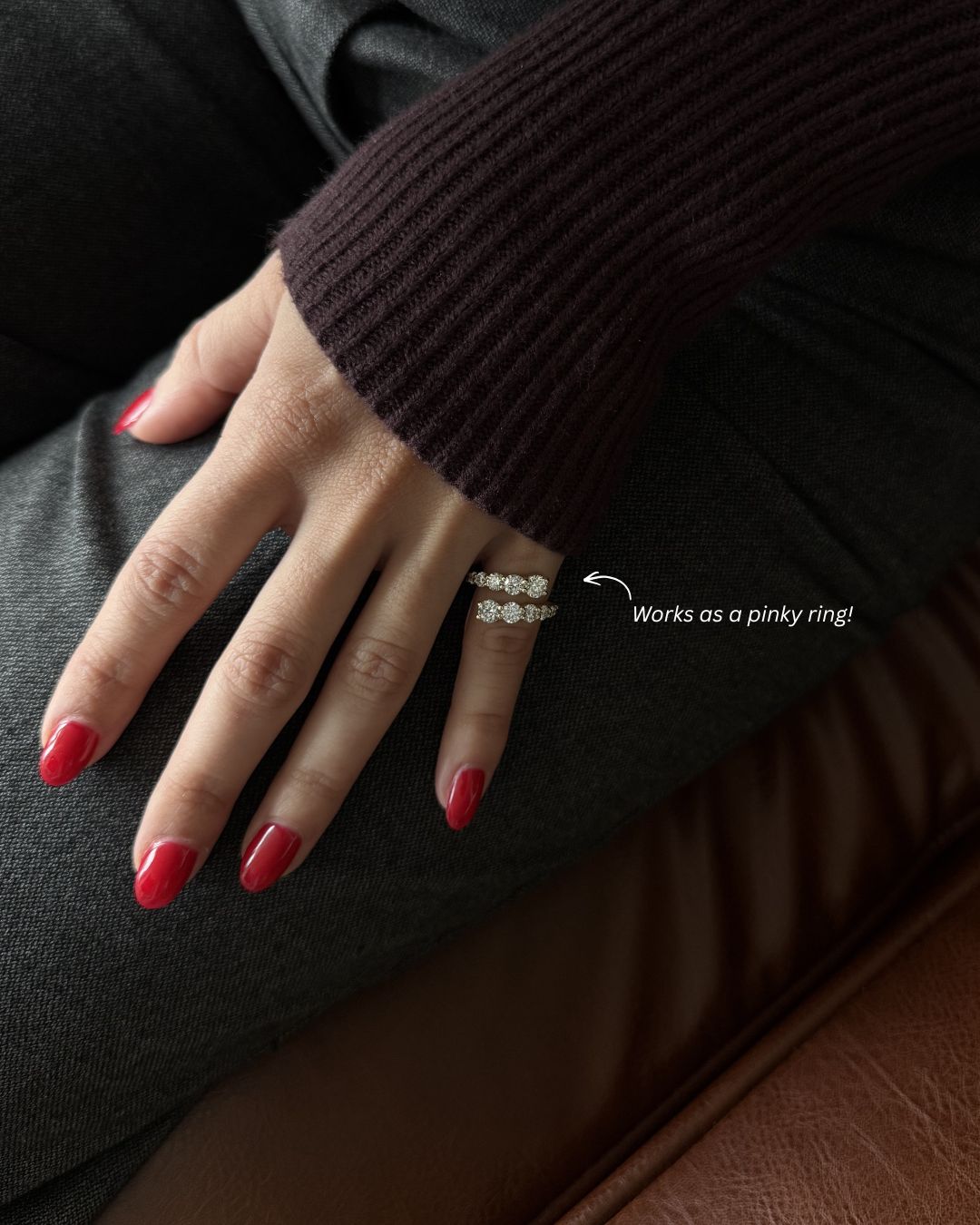 Gold moissanite open wrap ring worn as a pinky ring with red nails.