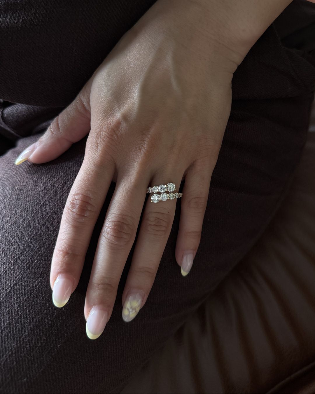 Gold moissanite open wrap statement ring worn on hand with neutral nails and burgundy knit styling.