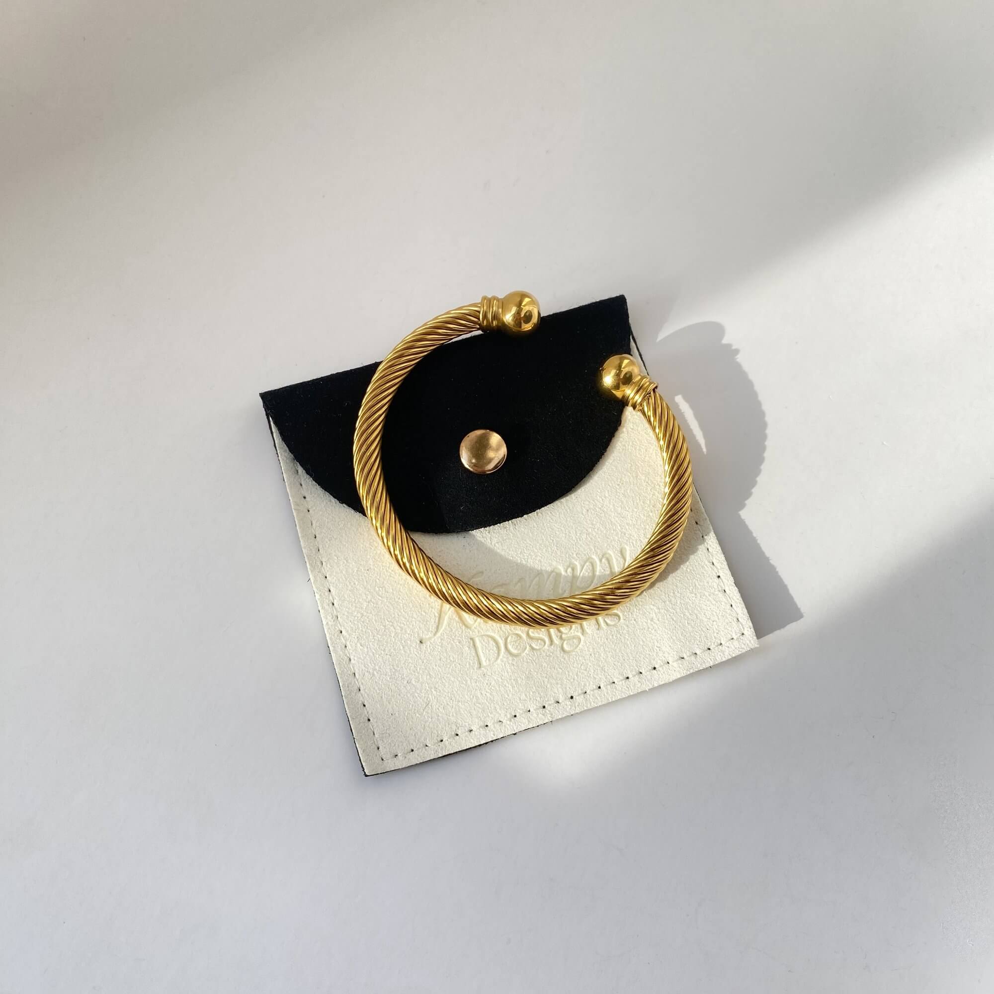 Branded flat lay of the KammyB gold twist cuff bracelet by Kampy Designs, beautifully arranged to highlight the brand and craftsmanship.