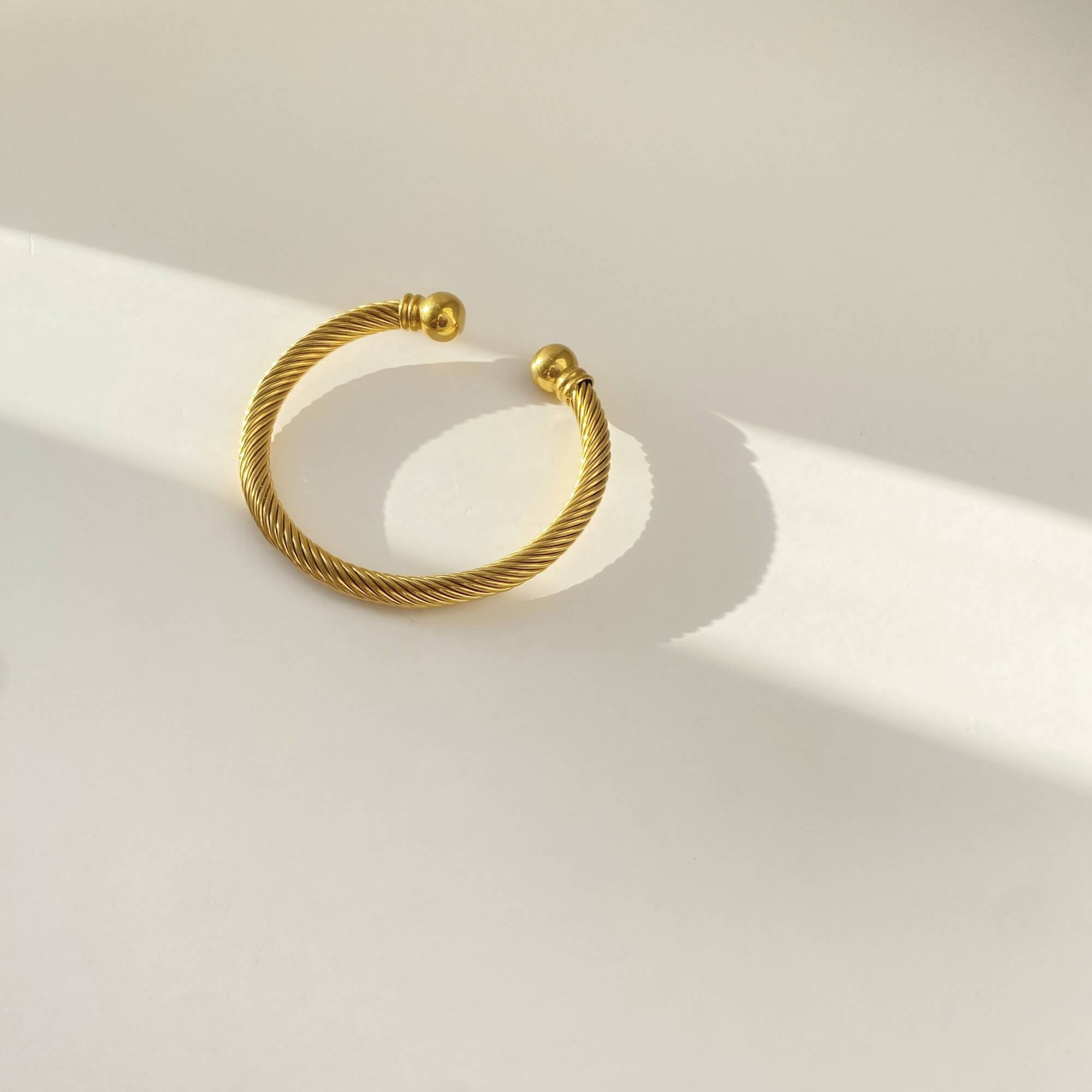Flat lay of the KammyB gold twist cuff bracelet by Kampy Designs, elegantly arranged to highlight its unique twisted design.