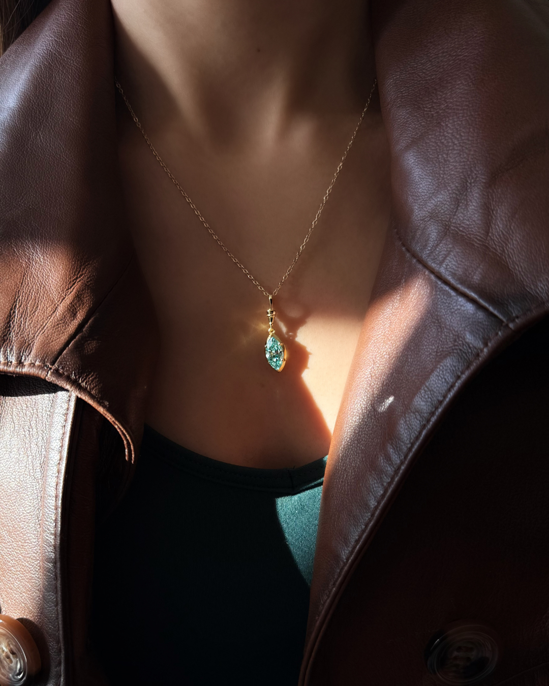 Green marquise moissanite pendant necklace in gold-plated 925 sterling silver worn with leather jacket by Kampy.