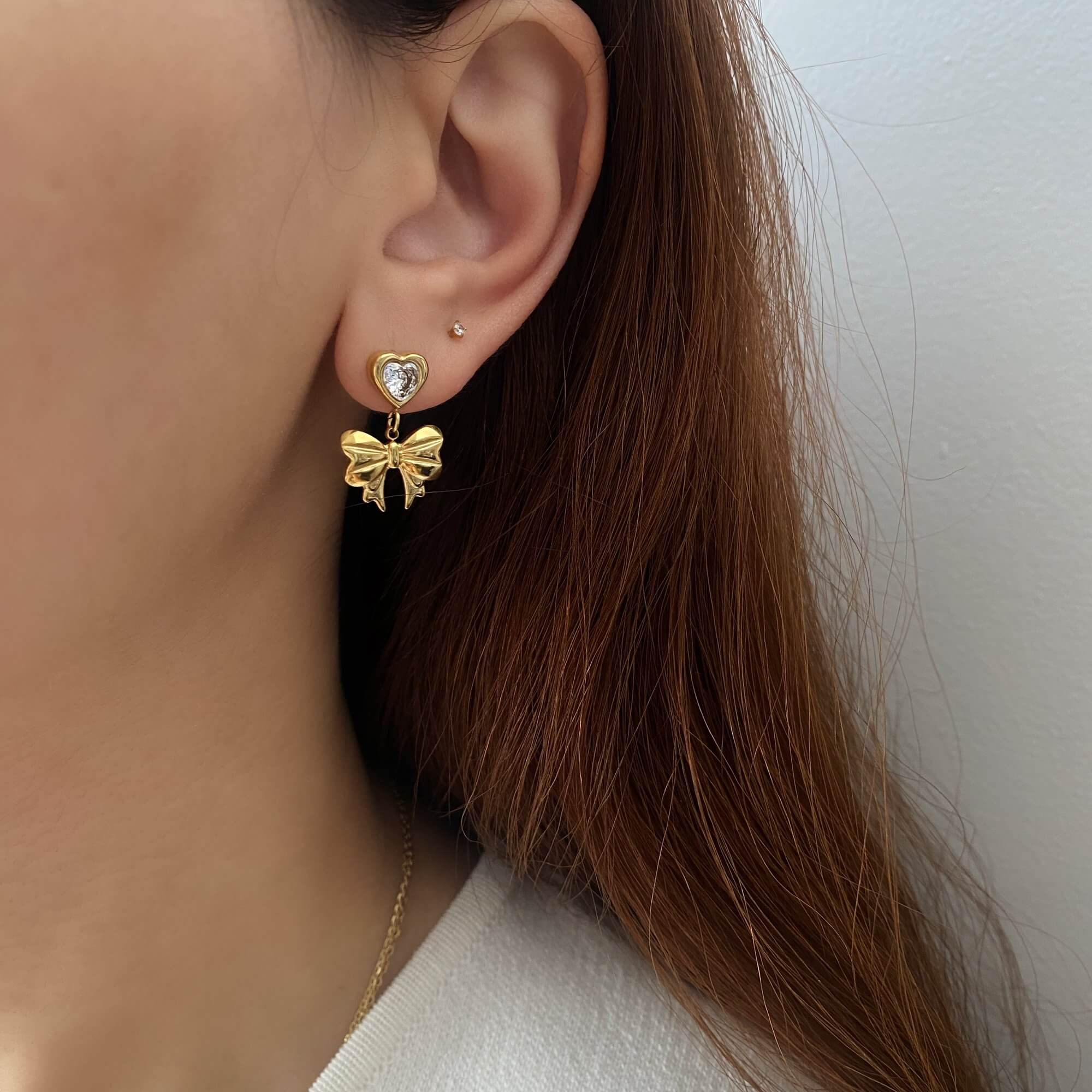 Far shot of KutieE heart bow dangle earrings by Kampy Designs, styled on model for an overall view of their elegant drop length and silhouette.