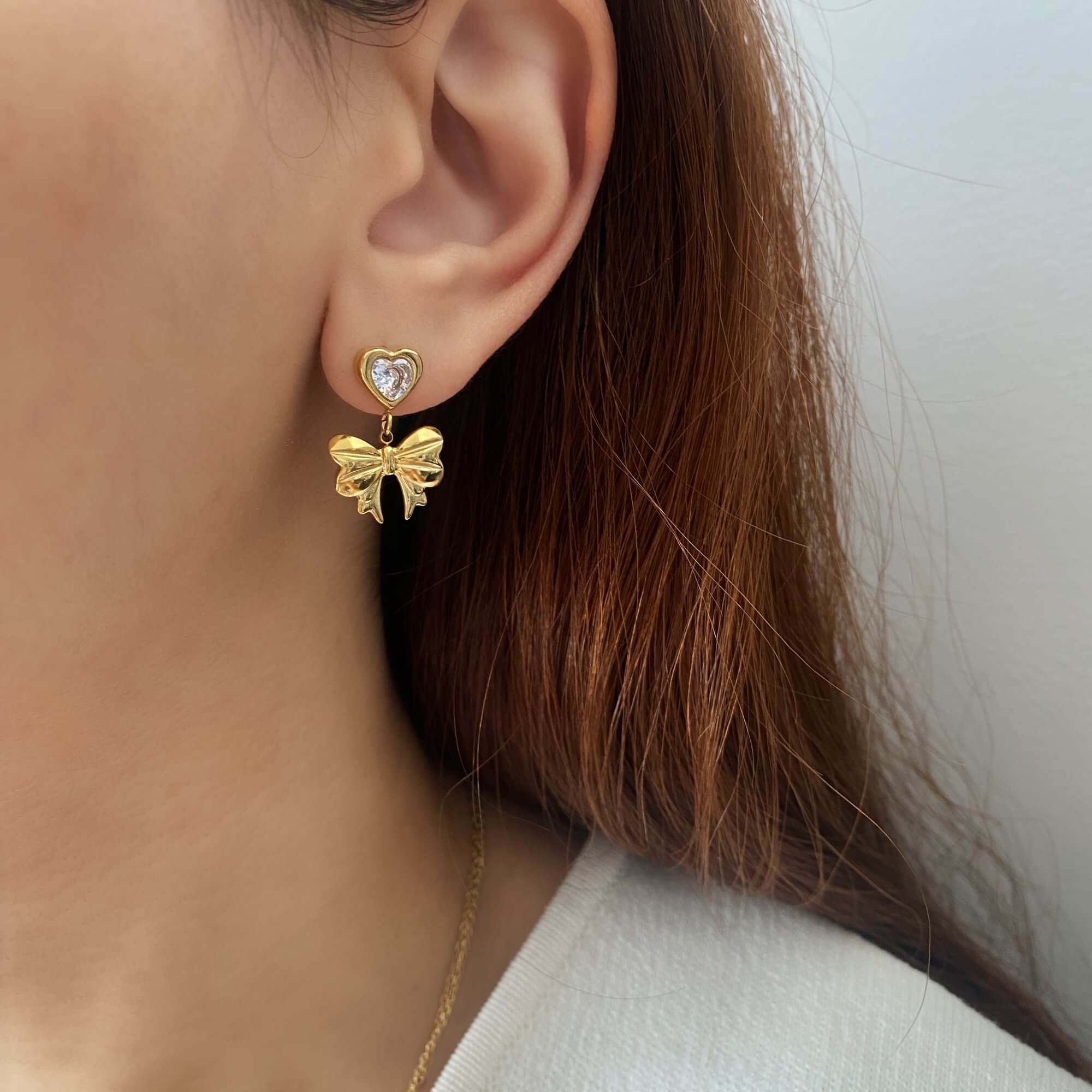 KutieE heart bow dangle earrings by Kampy Designs, worn by model to showcase the charming dual motif and feminine drop length.
