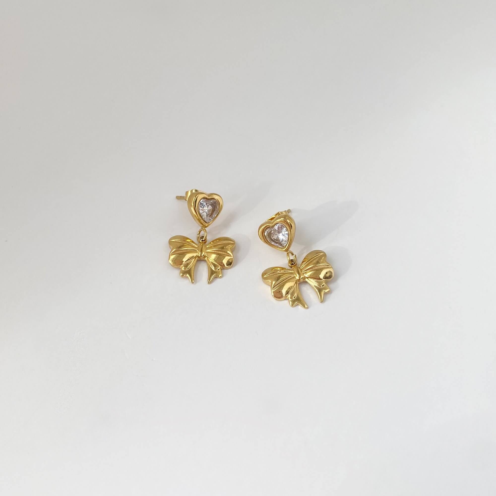 Flat lay of KutieE heart bow dangle earrings by Kampy Designs, capturing the playful heart charm and graceful bow design from above.