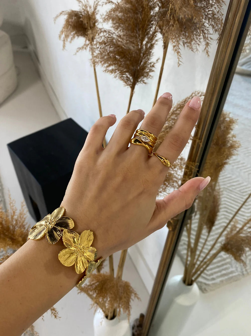 The KloraB hibiscus flower cuff bracelet by Kampy Designs, stacked with other bracelets to create a bold and stylish layered look.