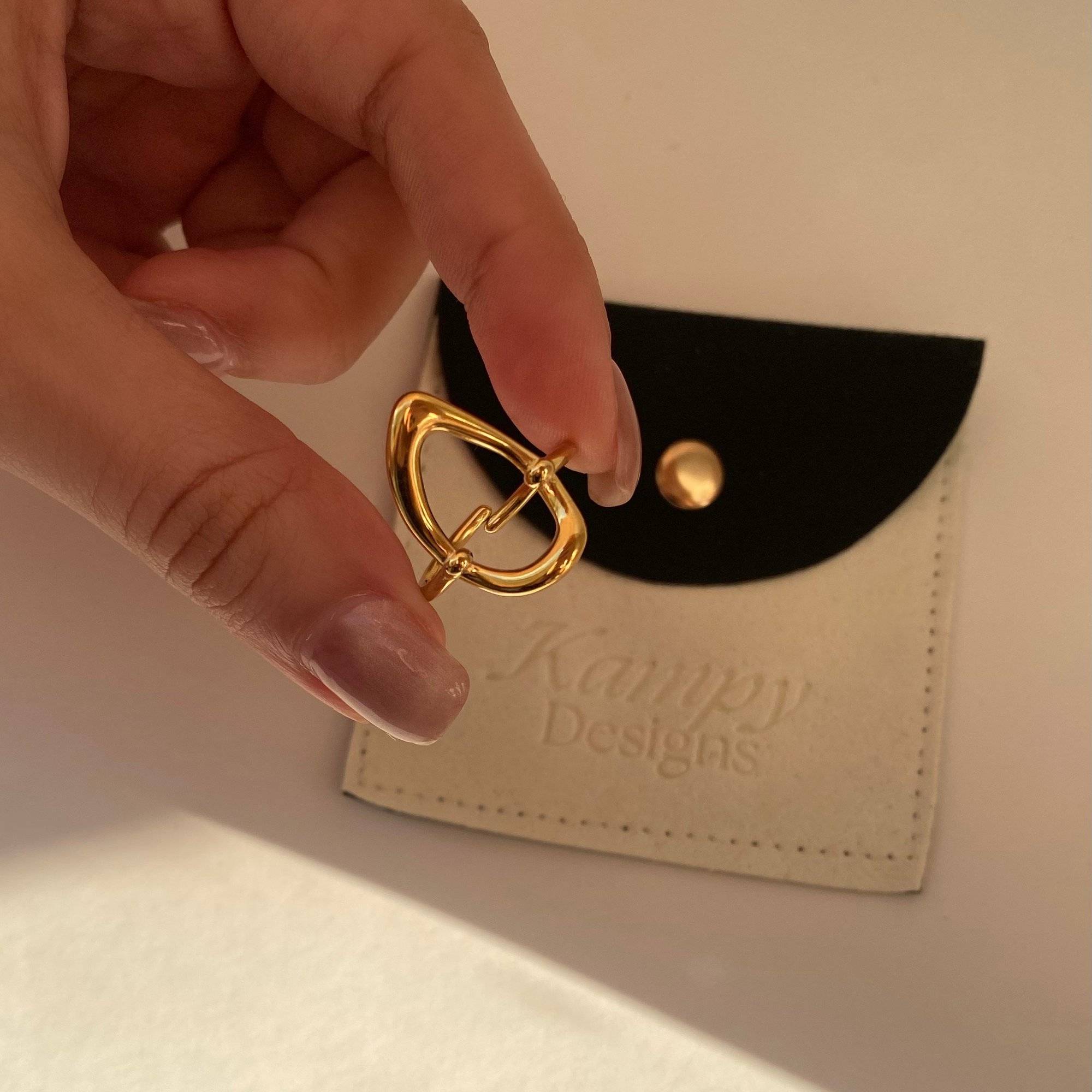 Angled hand-held view of KatyR hollow oval ring by Kampy Designs, capturing the delicate geometry and artistic style.