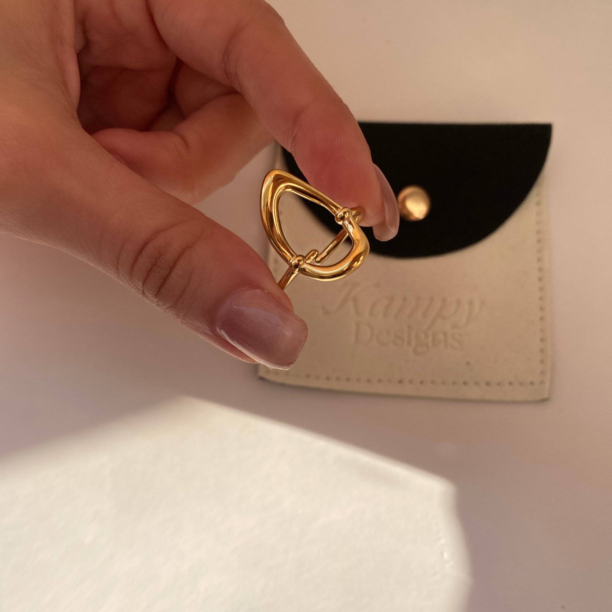 Side perspective of KatyR hollow oval ring by Kampy Designs, held in hand to reveal its fine cut and metal detailing.