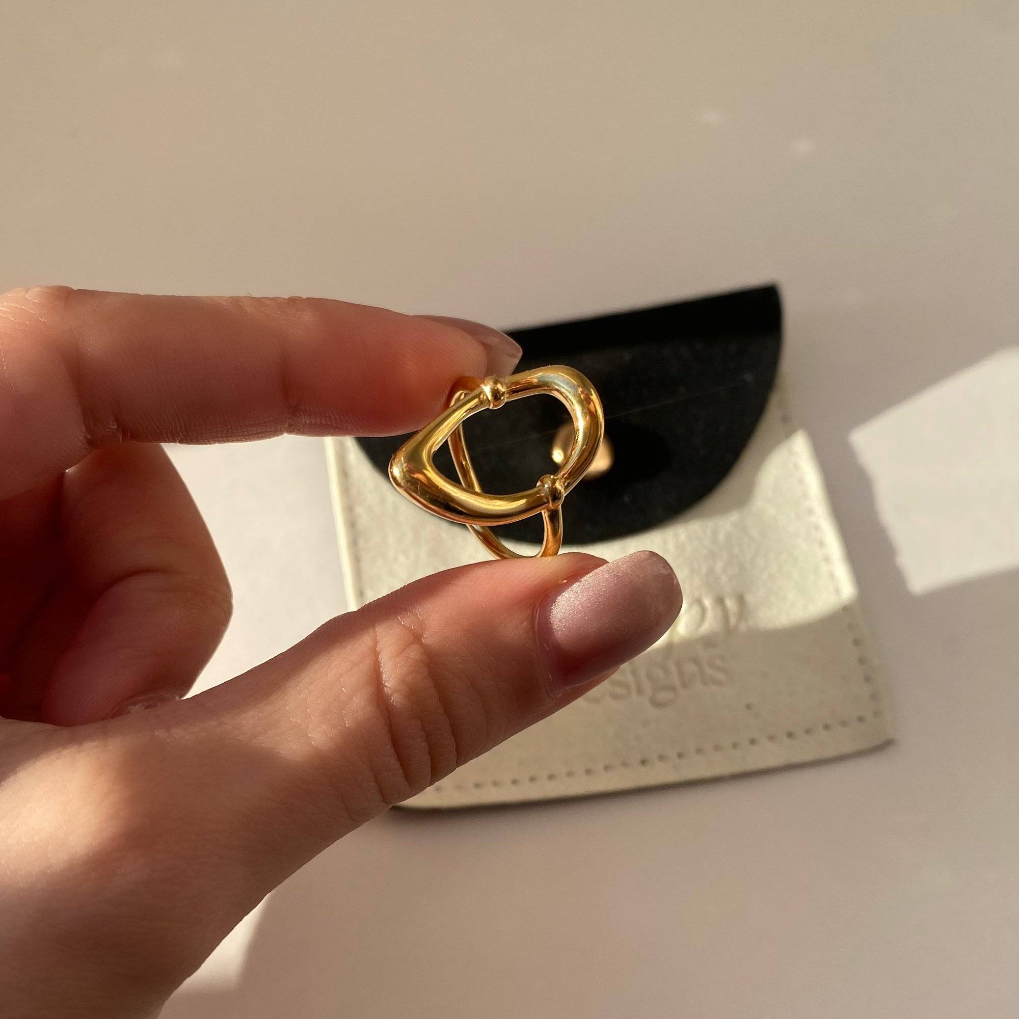 Side perspective of KatyR hollow oval ring by Kampy Designs, held in hand to reveal its fine cut and metal detailing.