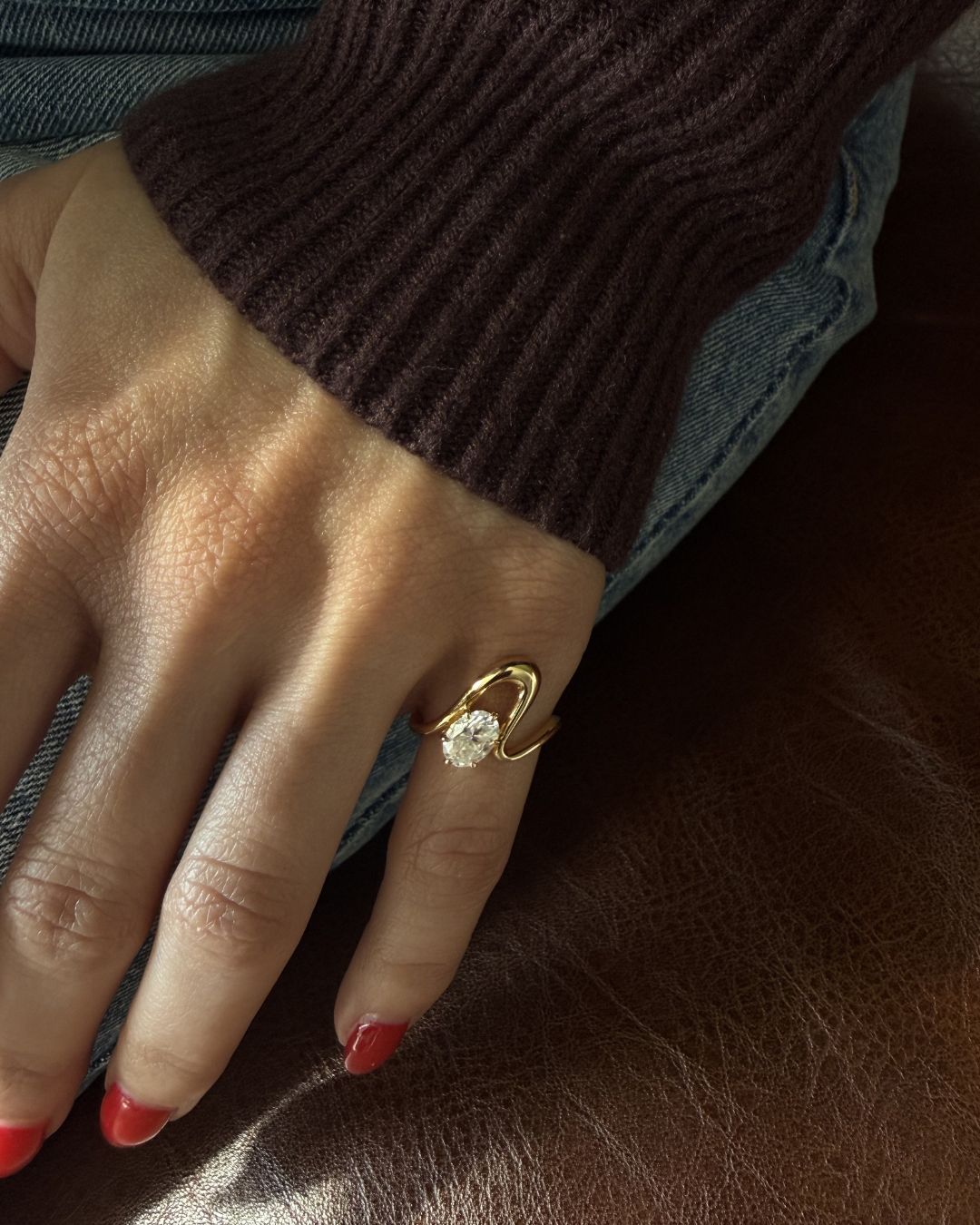 Clean girl aesthetic gold pinky ring with oval moissanite worn on hand in a minimal styling look