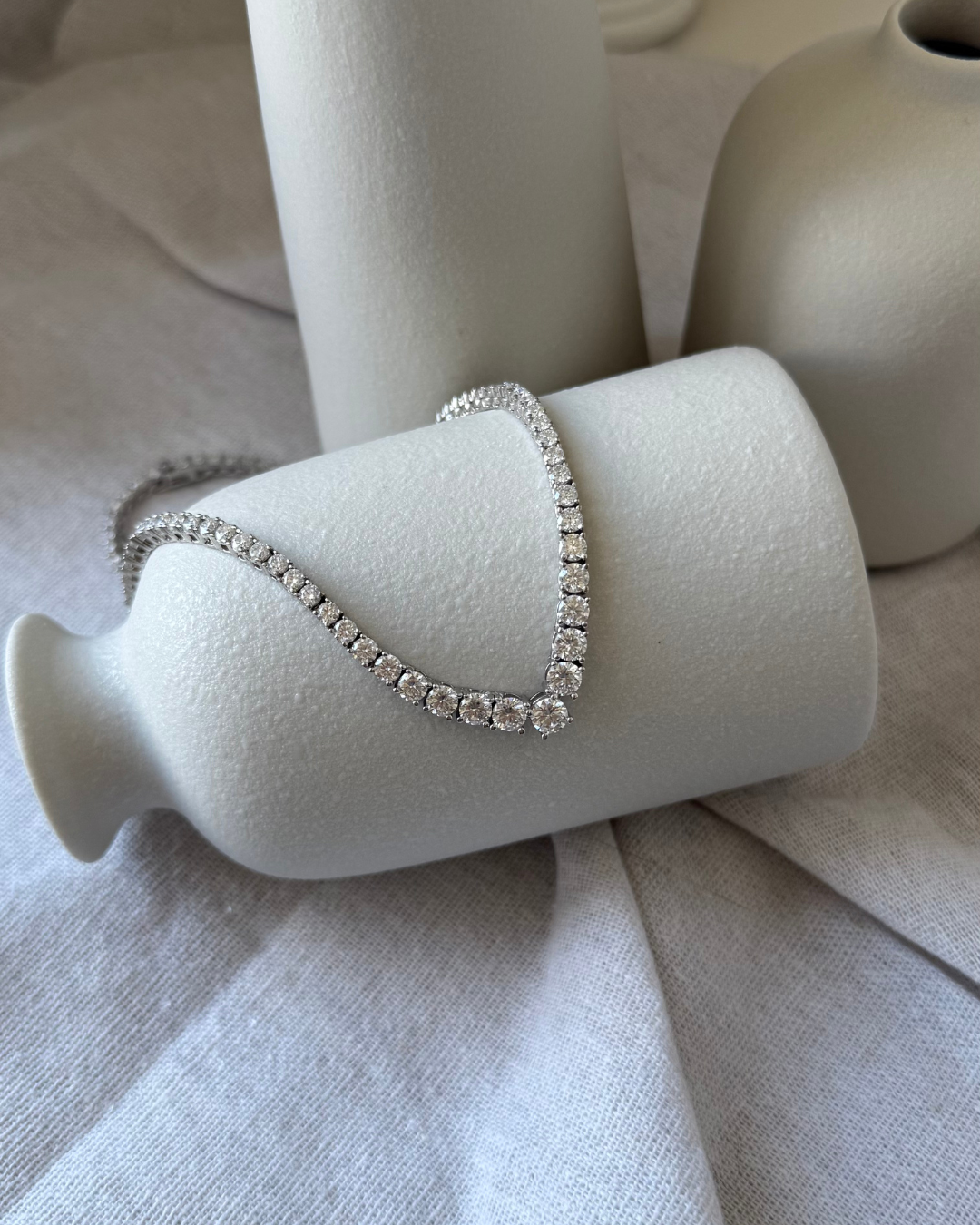 moissanite tennis necklace on a white jewelry display stand with a neutral background