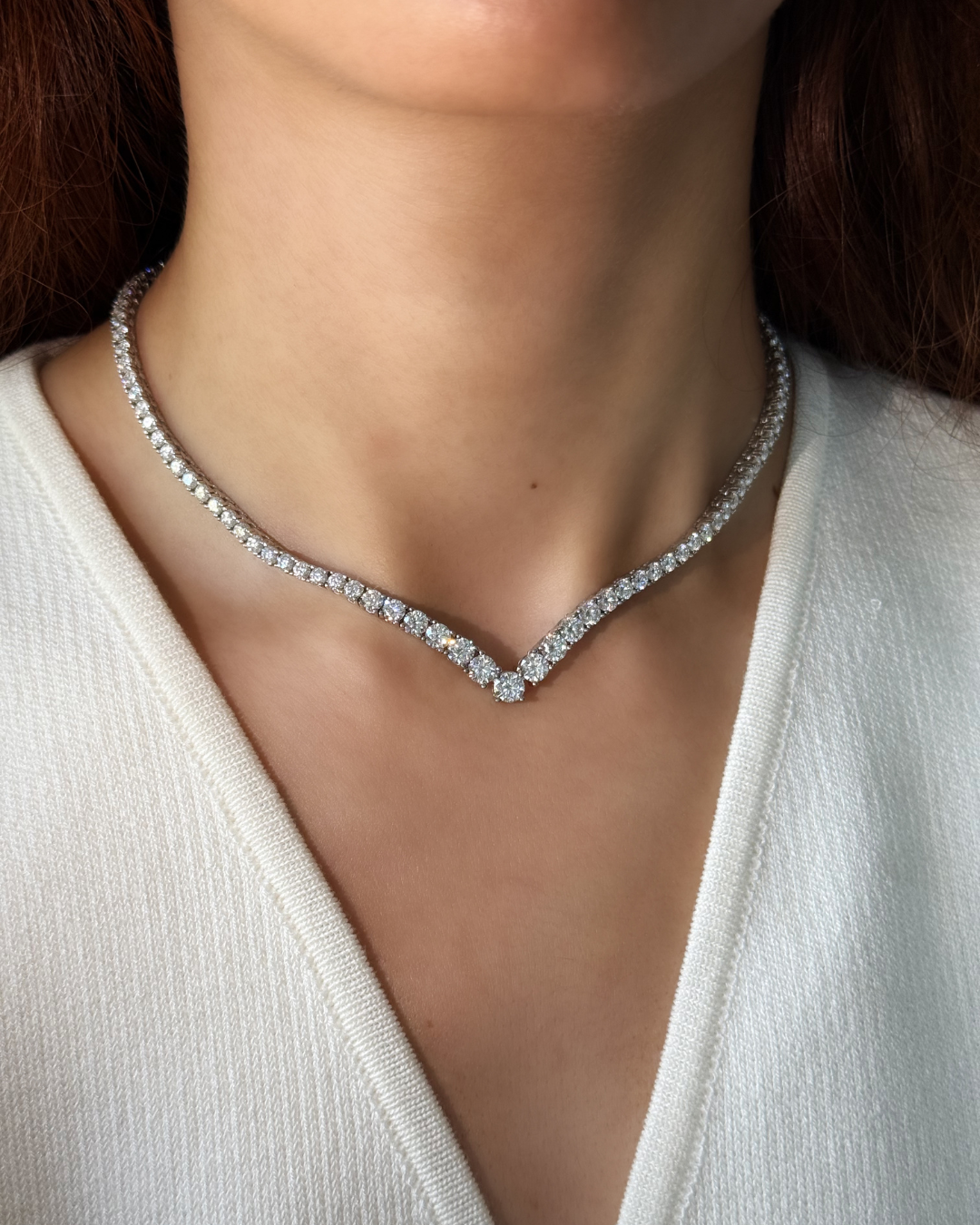 Diamond necklace worn by a person against a neutral background