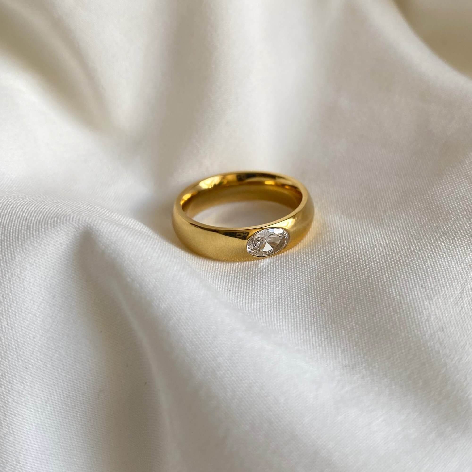 Side view of the KimmyR oval diamond cigar band ring by Kampy Designs, showcasing its thick gold band and striking oval-cut diamond centerpiece.