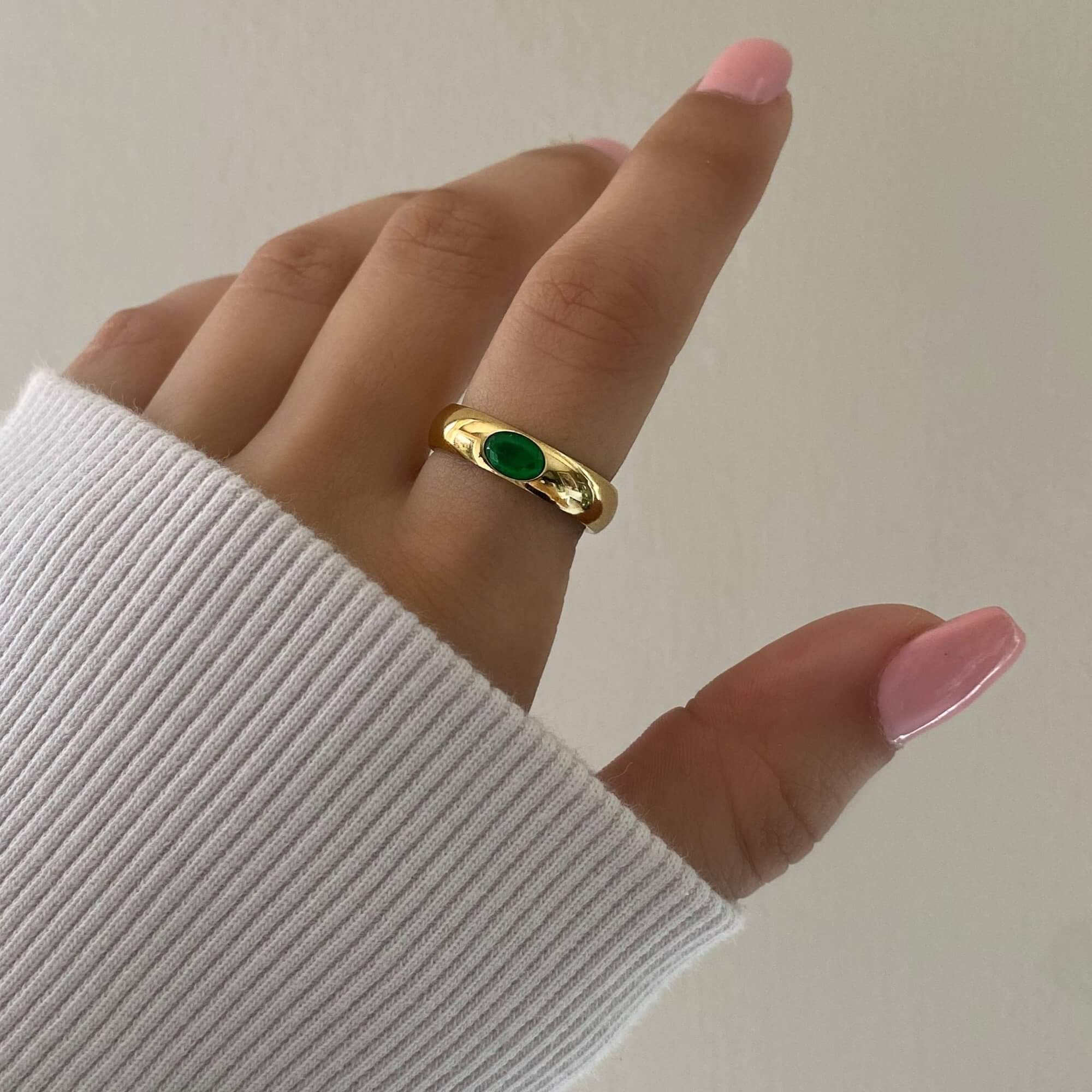 The KimmyR oval emerald cigar band ring by Kampy Designs, worn to highlight its rich green gemstone and modern cigar band style.