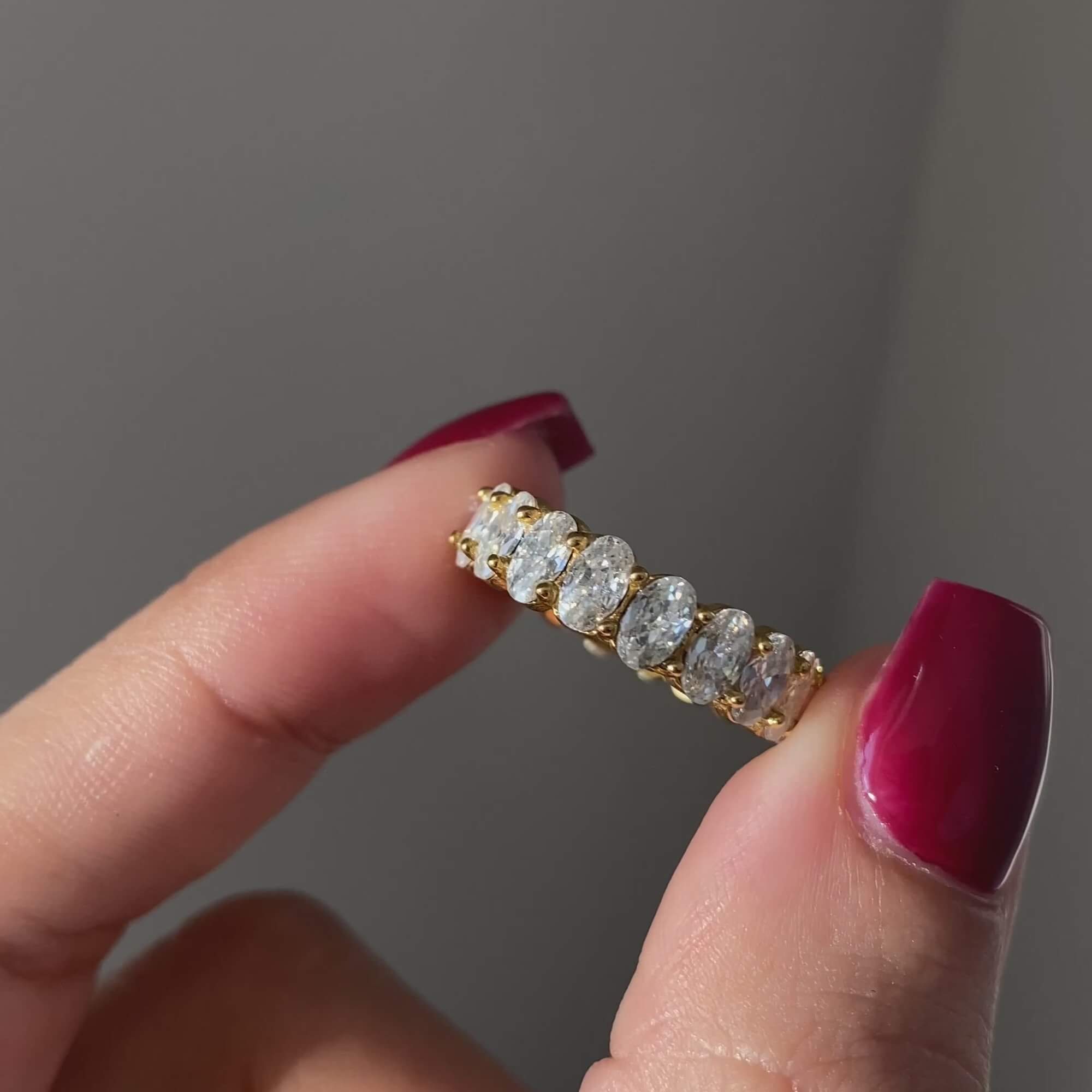 The KastielR oval diamond eternity ring by Kampy Designs, delicately held to highlight its exquisite craftsmanship and dazzling diamonds.