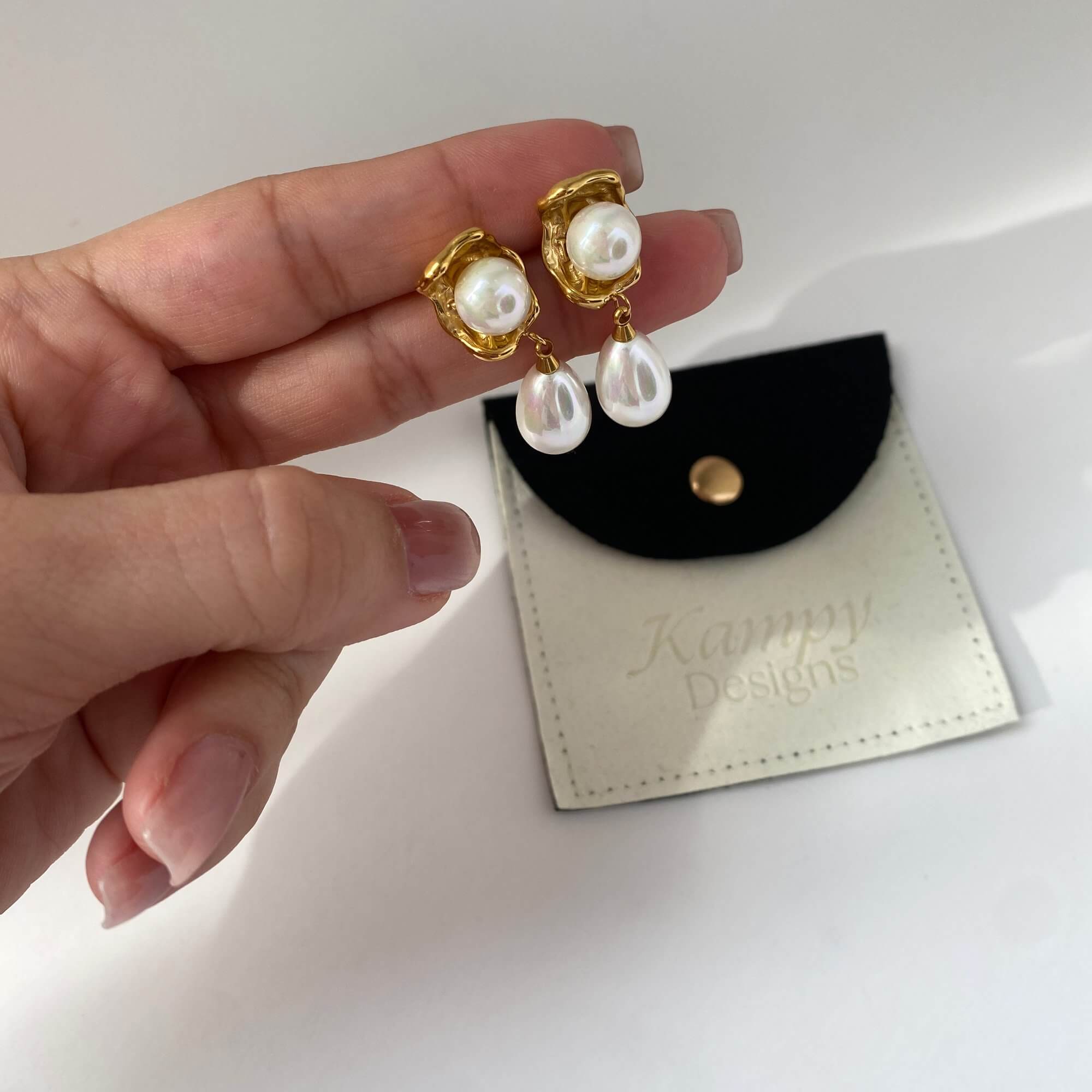 Angled shot of KearyE oyster pearl dangle earrings by Kampy Designs, capturing the reflective luster of the pearl and shell detail.
