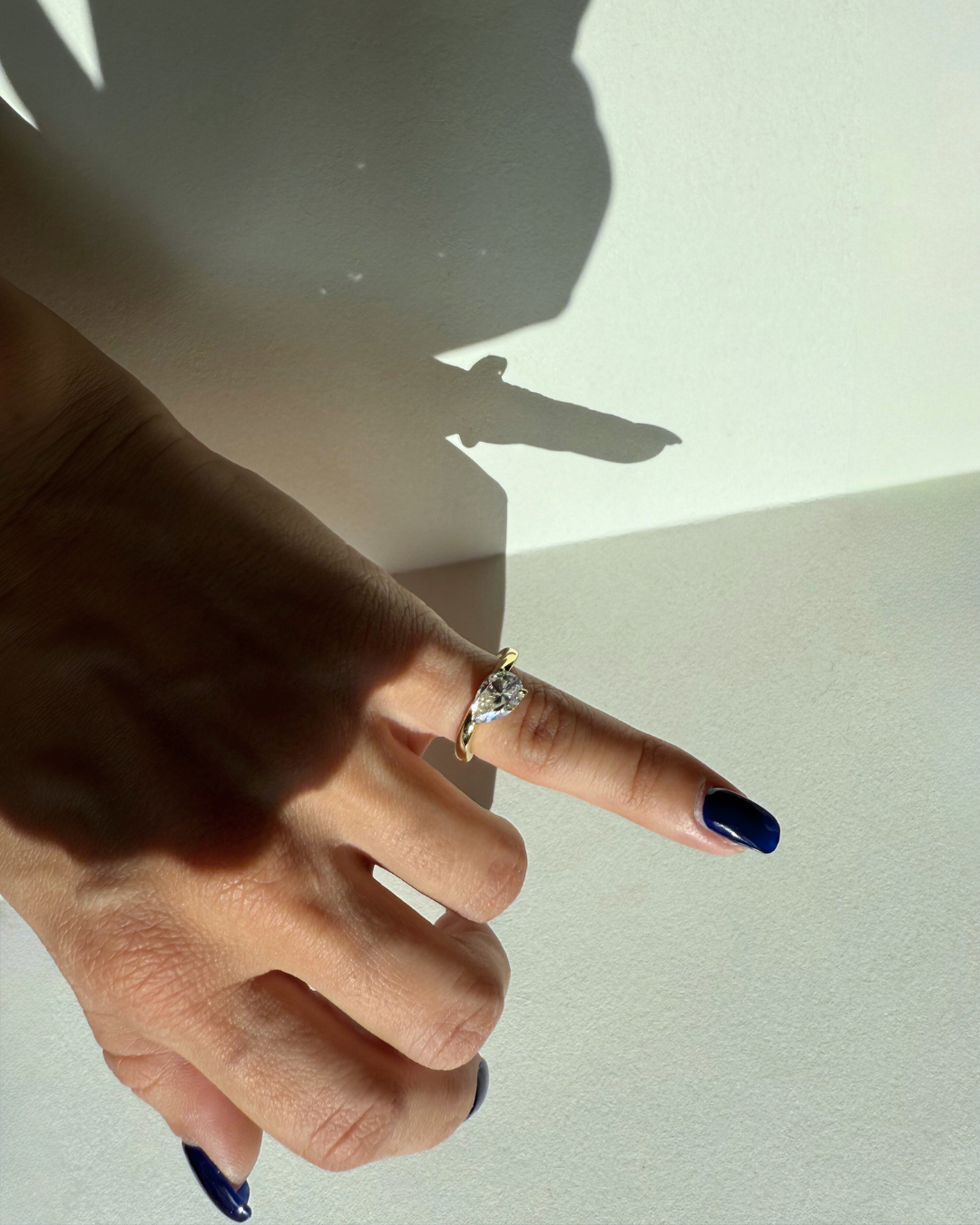 East-west pear cut moissanite wave ring worn on pinky finger from alternate angle, Kampy Designs