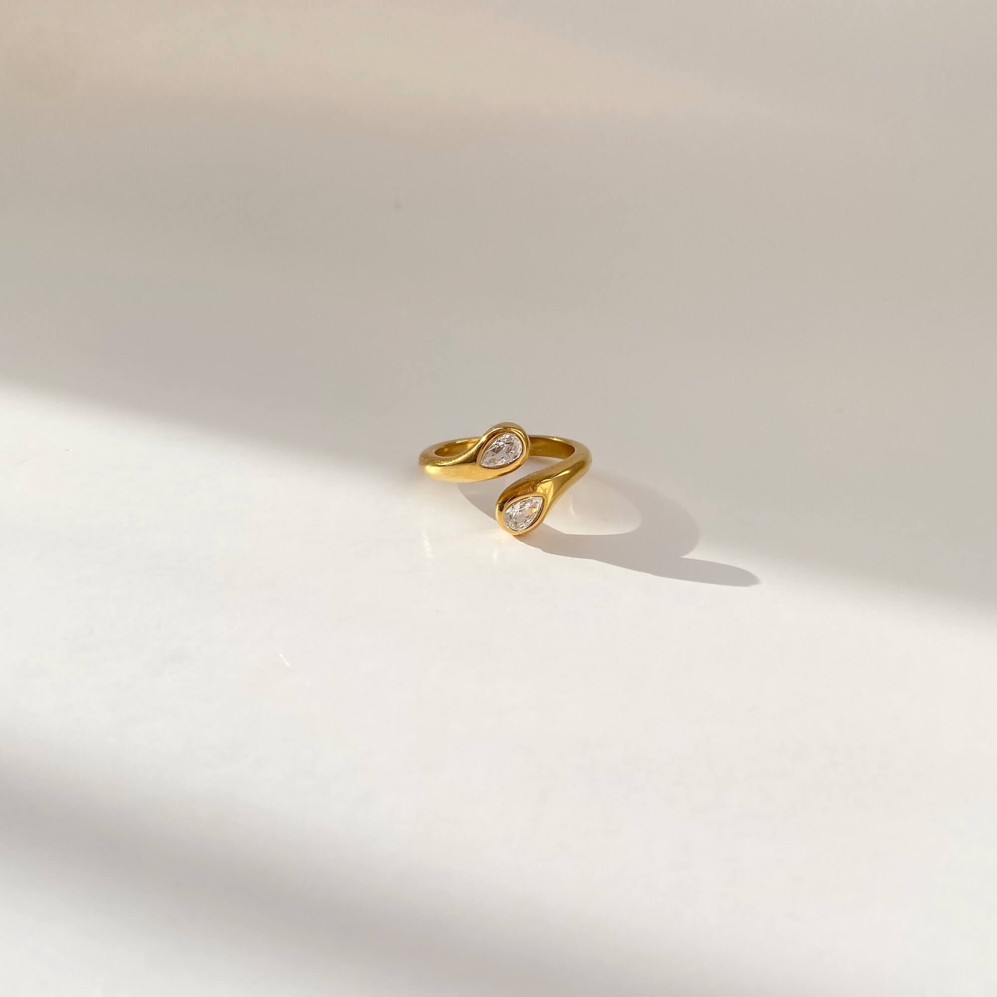 Flat lay of the Kamilar pear wrap ring by Kampy Designs, showcasing its modern open-wrap silhouette and gleaming finish.