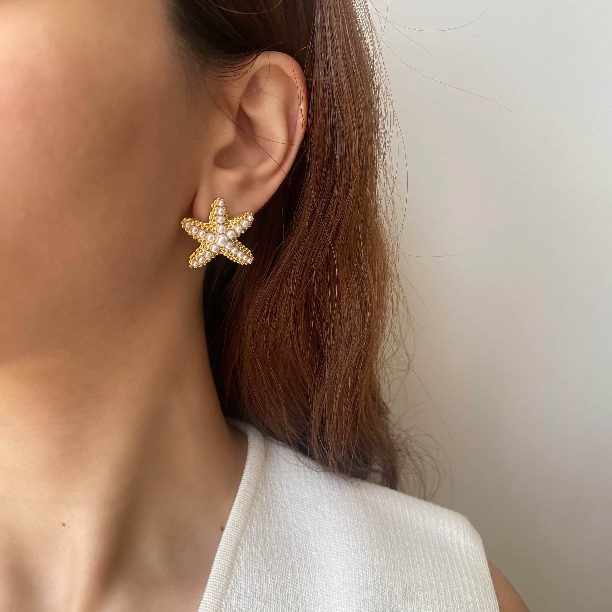 Angled view of KeachyE pearl starfish earrings by Kampy Designs, worn on model’s ear to highlight the oceanic shape and pearlescent charm.
