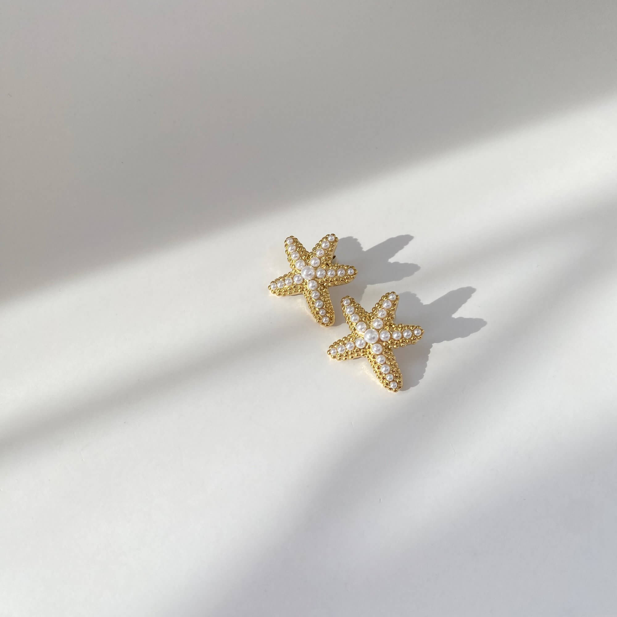 Angled product view of KeachyE pearl starfish earrings by Kampy Designs, emphasizing the texture and oceanic theme.